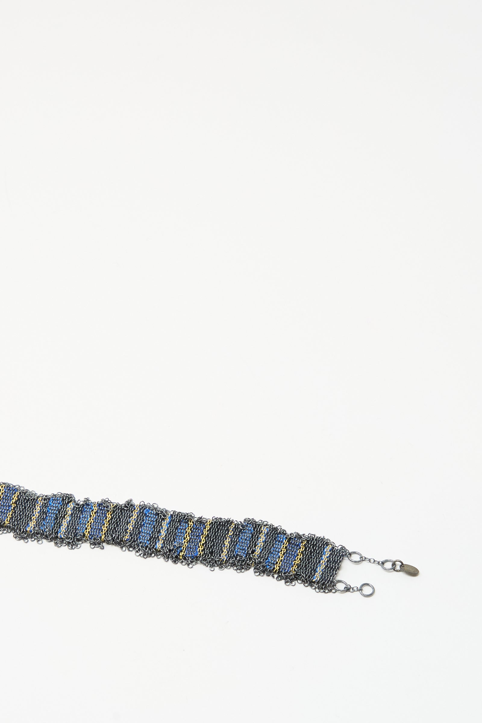 The Stephanie Schneider Silver and Silk Woven Bracelet in Blue features a wide graphic chain with blue and yellow accents and a clasp, shown on a white background.