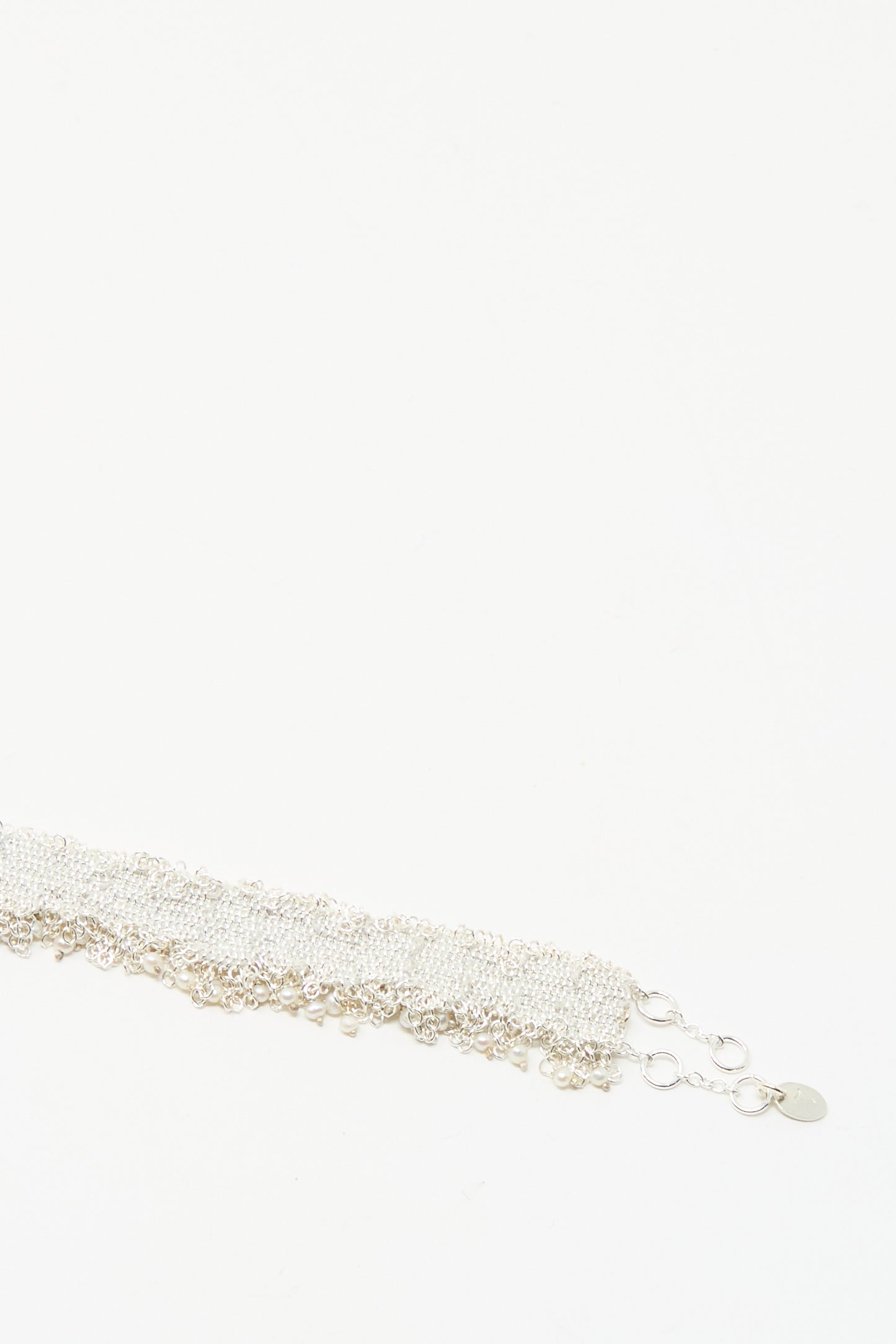 The Stephanie Schneider Silver and Silk Woven Bracelet with Pearls features multiple linked strands and a clasp, displayed against a plain white background.