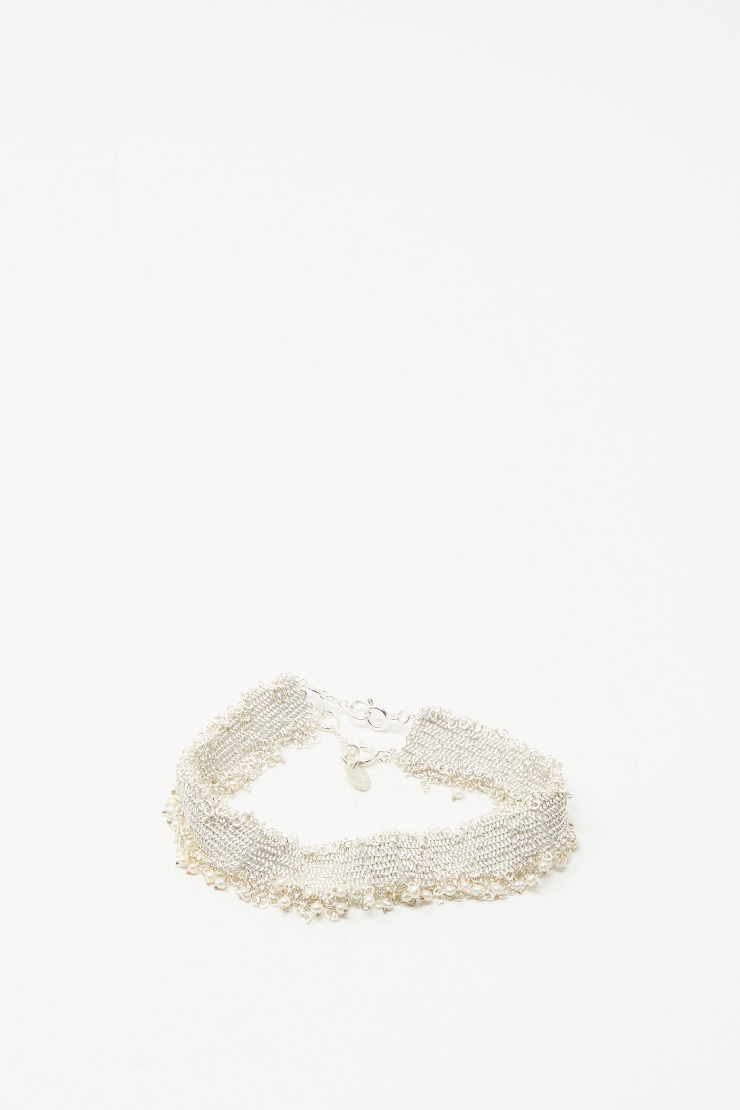 The Silver and Silk Woven Bracelet with Pearls by Stephanie Schneider features a textured sterling silver design with dangling pearls, displayed on a plain white background.