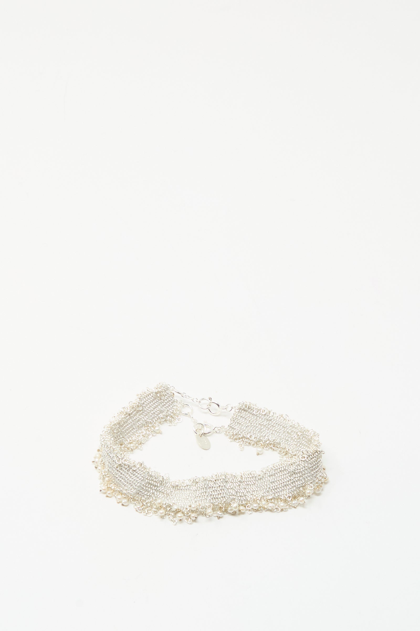 The Silver and Silk Woven Bracelet with Pearls by Stephanie Schneider features a textured sterling silver design with dangling pearls, displayed on a plain white background.
