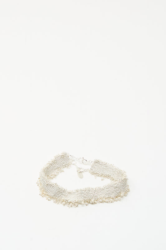 The Silver and Silk Woven Bracelet with Pearls by Stephanie Schneider features a textured sterling silver design with dangling pearls, displayed on a plain white background.