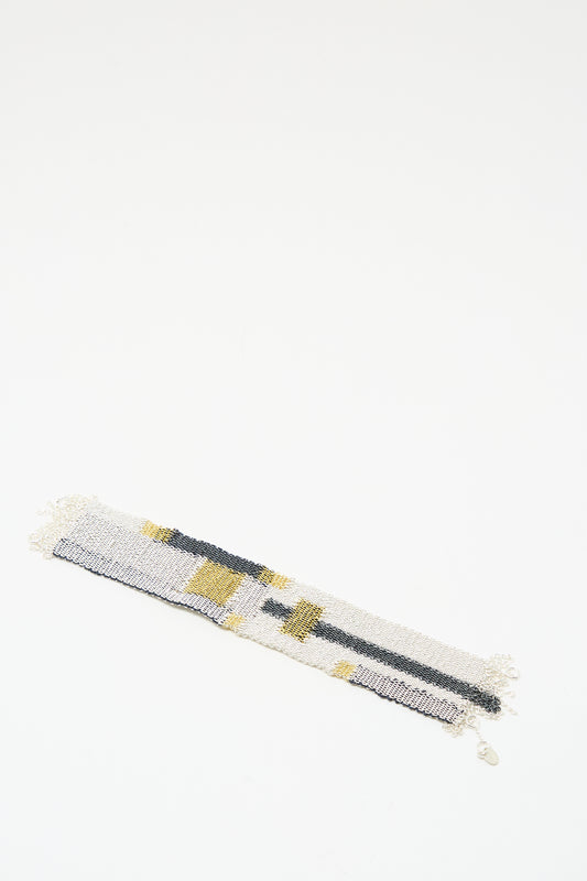 The Stephanie Schneider Silver Oxidized, Gold Plated and Silk Woven Bracelet with geometric gray, white, and yellow patterns is displayed on a white background.