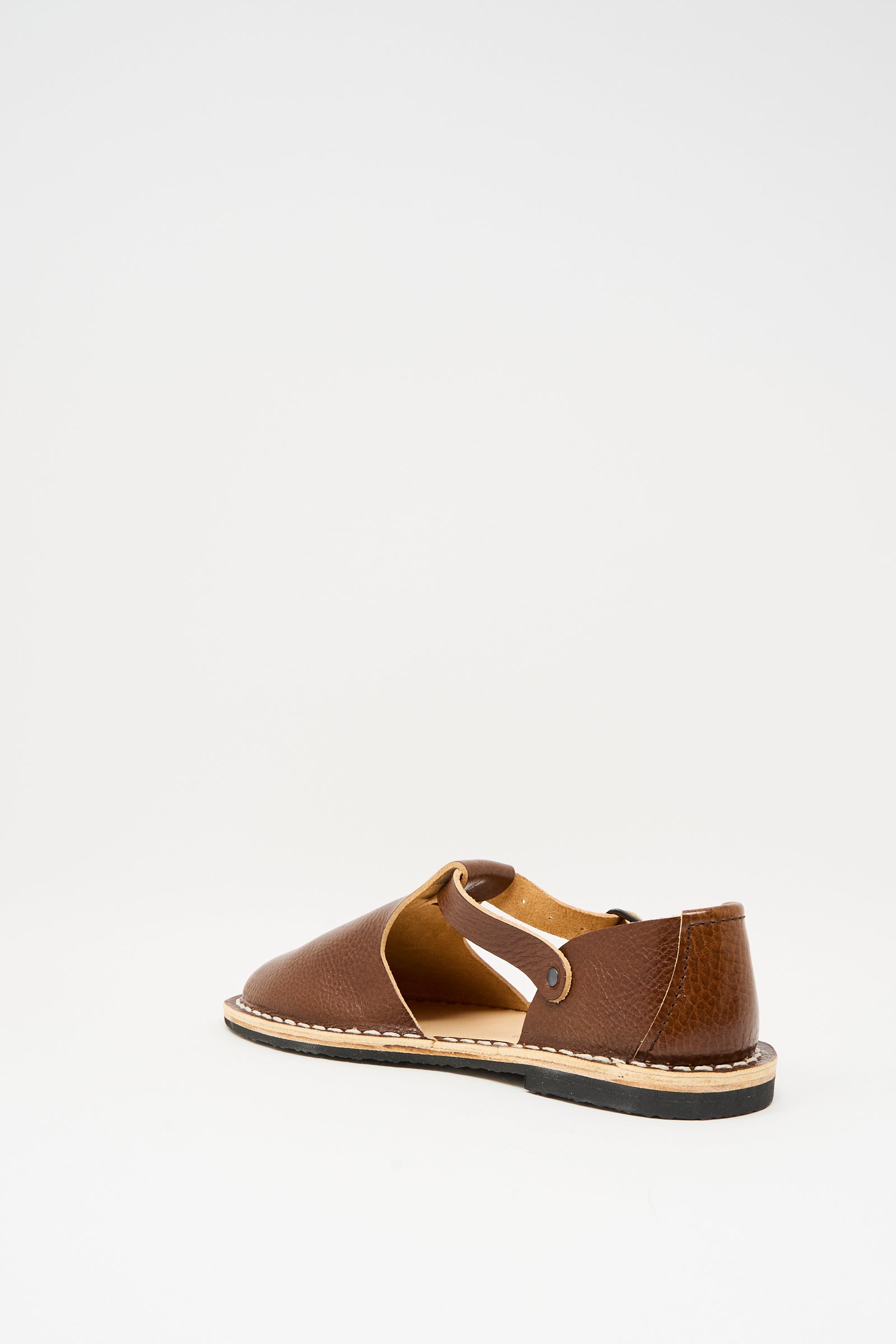 A single Steve Mono Artisanal Sandal 10/12 in Brandy, crafted from vegetable-tanned leather with an open side and black recycled rubber sole, displayed on a plain white background.