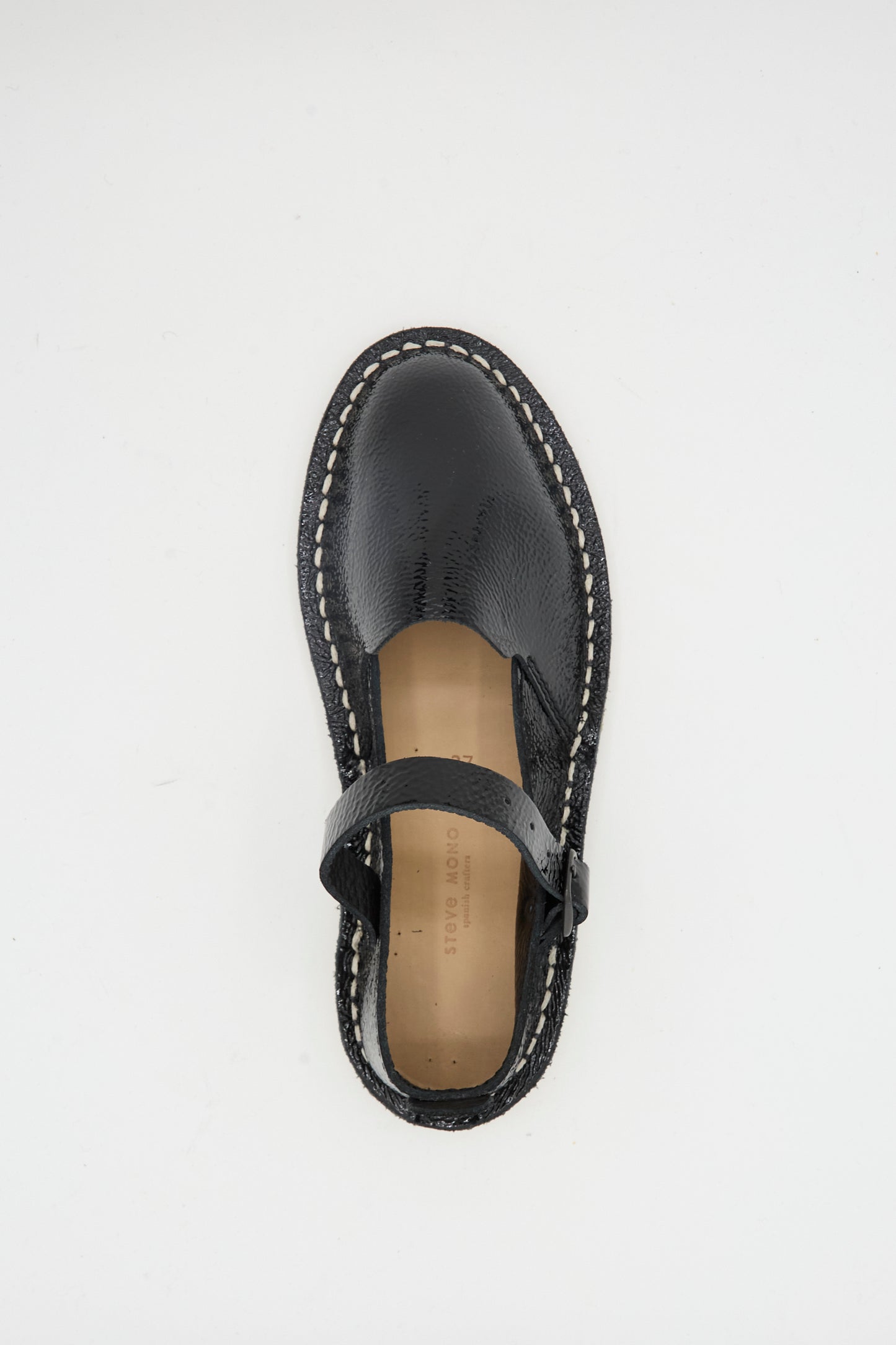 The Steve Mono Mary Jane in Glossy Black features white stitching and a recycled rubber sole, shown from above on a plain white background.