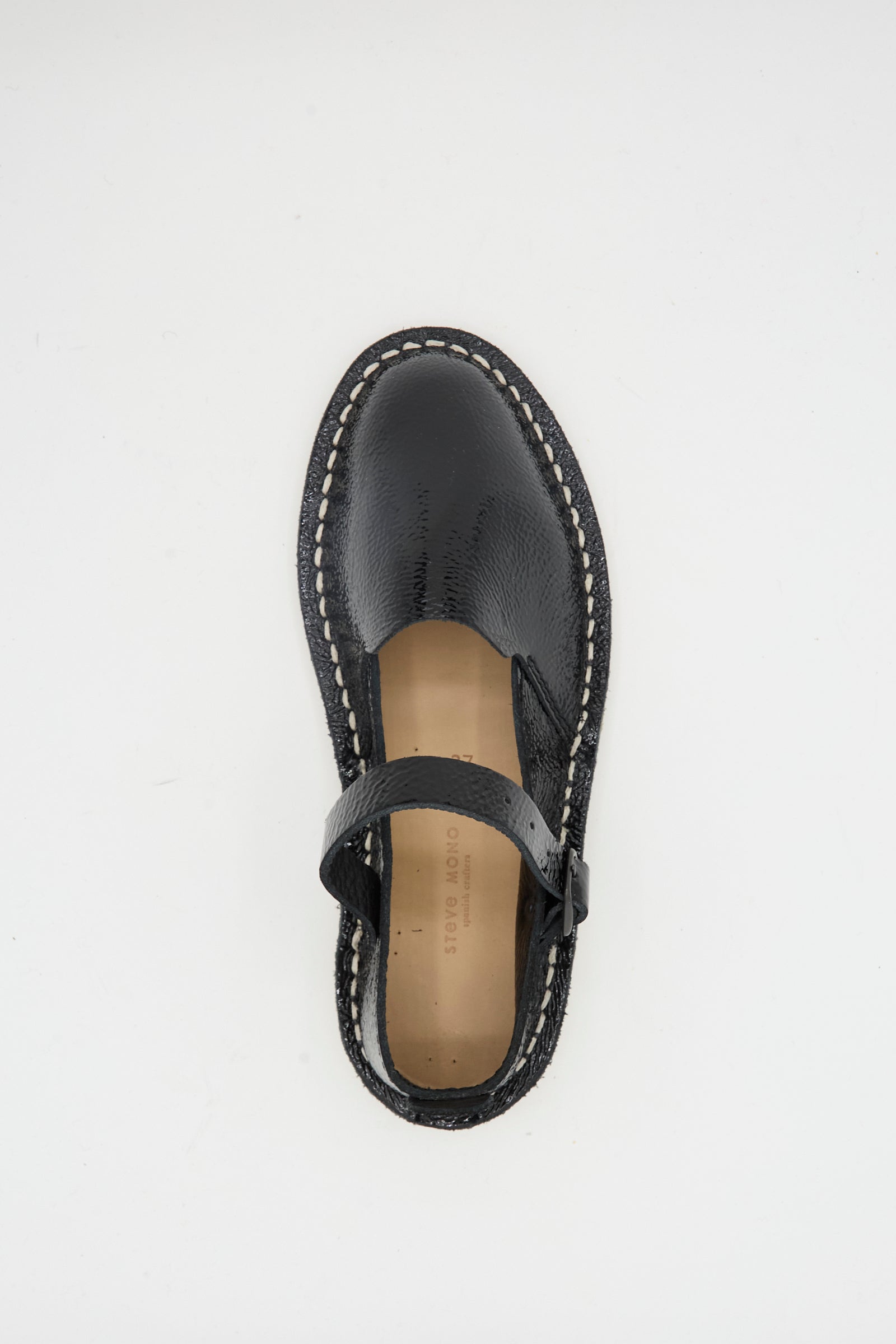The Steve Mono Mary Jane in Glossy Black features white stitching and a recycled rubber sole, shown from above on a plain white background.