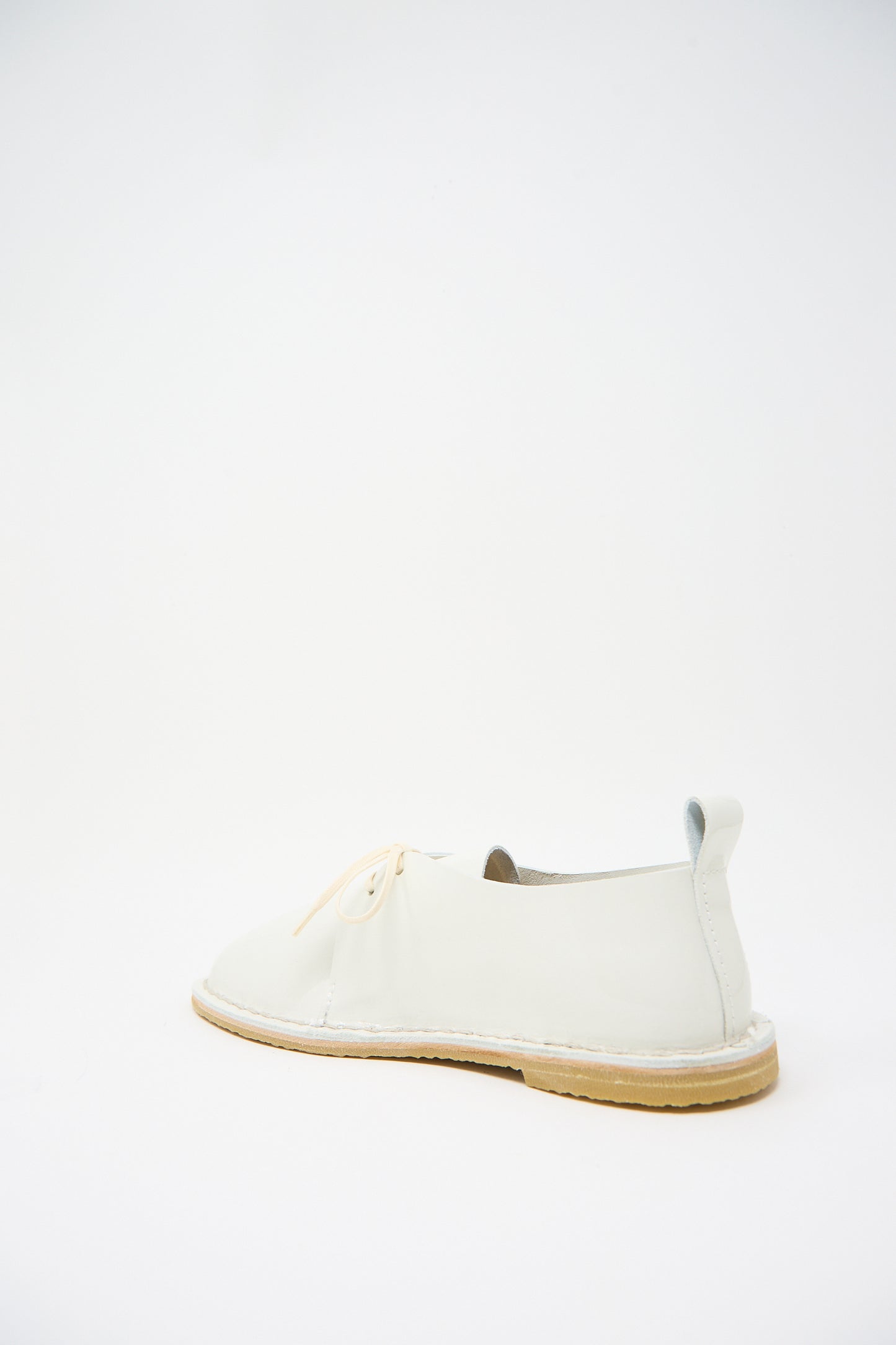 A single Steve Mono Patent Leather Derbie in White with a beige sole and laces, displayed against a plain white background, showcases its sleek design and sustainable craftsmanship.