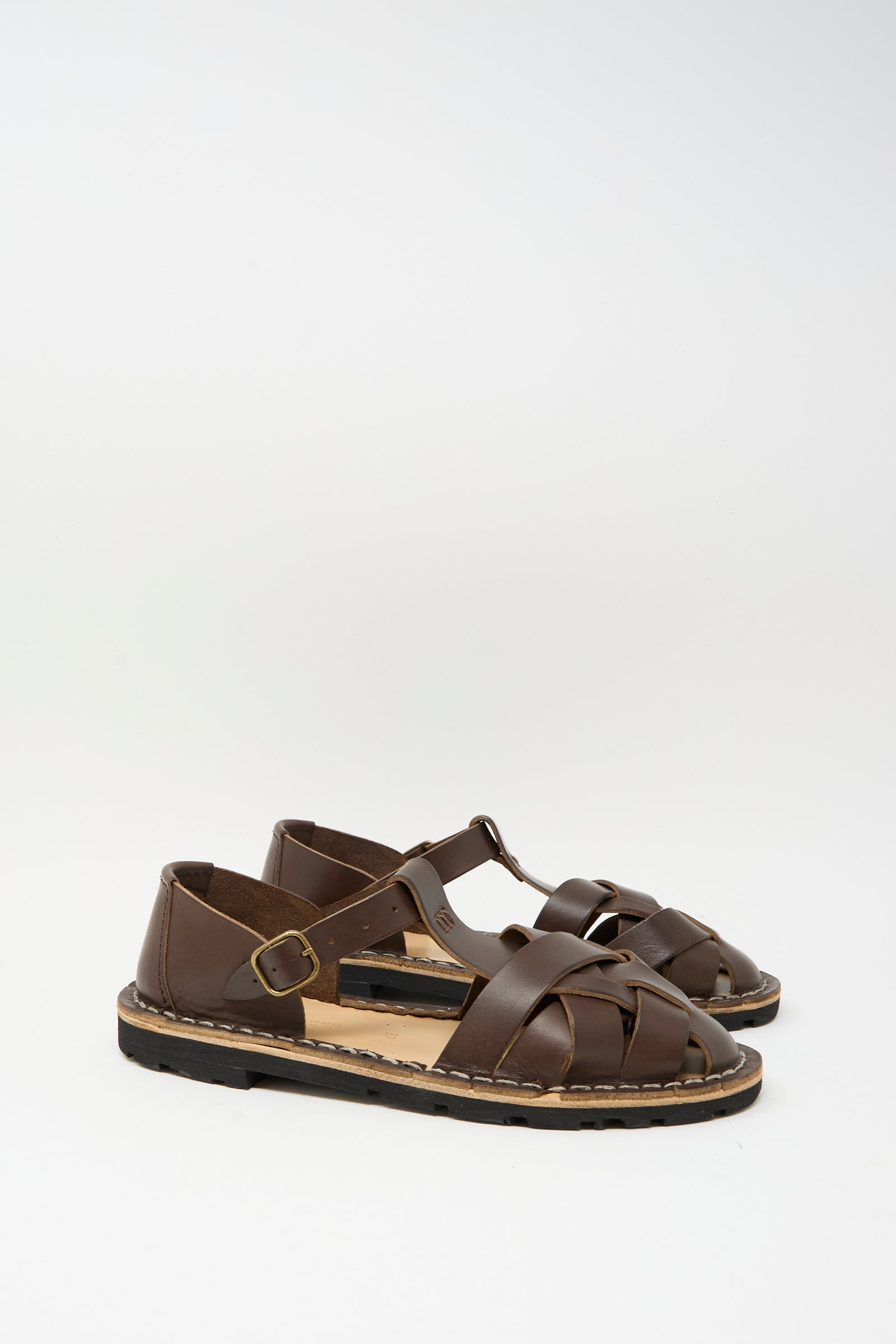 The Steve Mono Woven Leather Sandals in Dark Coffee—crafted in Spain with vegetable-tanned leather, buckled straps, and closed toes—are displayed on a plain white background.