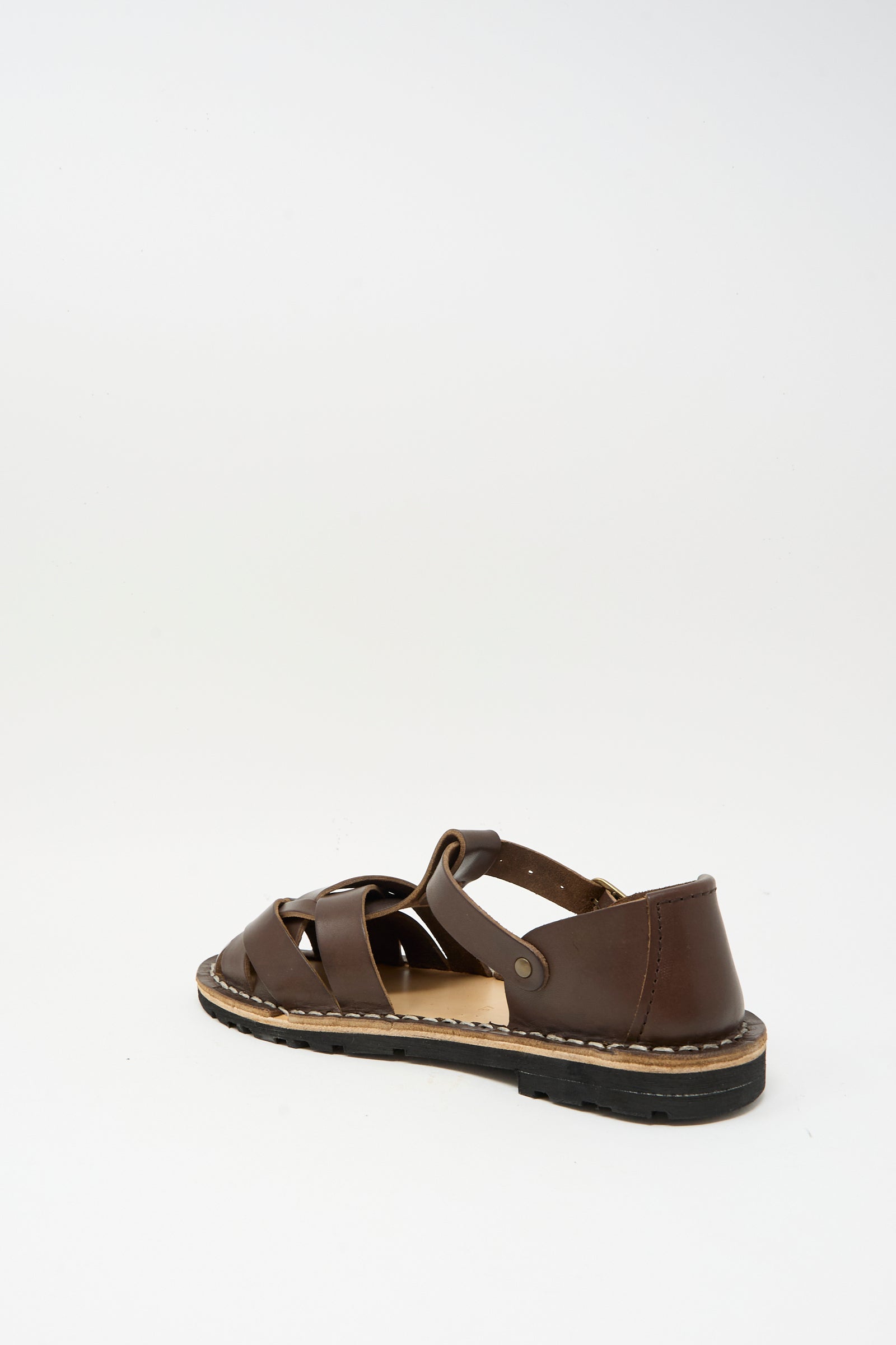 A single Steve Mono Woven Leather Sandal in Dark Coffee, featuring a closed toe and buckle strap, crafted from vegetable-tanned leather, is displayed on a plain white background.