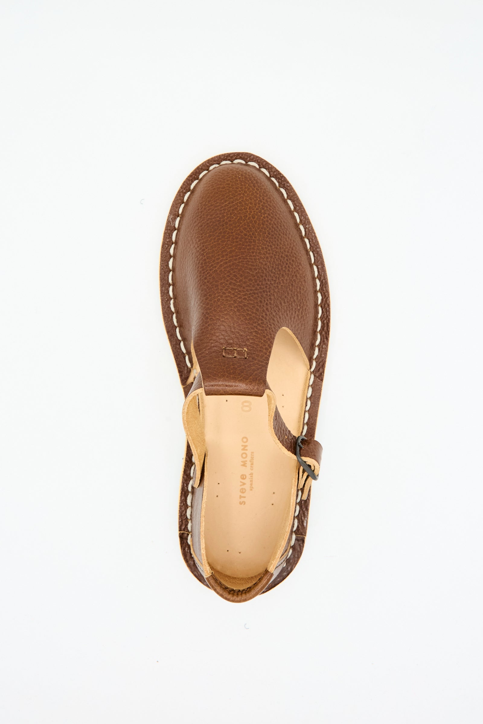 The Steve Mono Artisanal Sandal 10/12 in Brandy is shown from above, crafted from vegetable-tanned leather with white stitching and a recycled rubber sole, displayed on a plain white background.