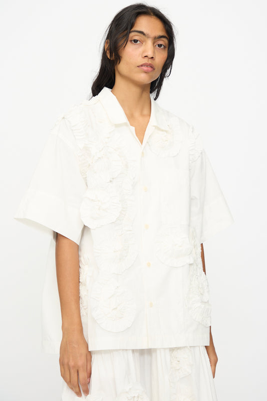 A person wears the Hand Applique Greetings Shirt in Ecru Fossil by Story mfg.—an oversized, short-sleeved white shirt with textured circular ruffle appliques—standing against a plain white background.