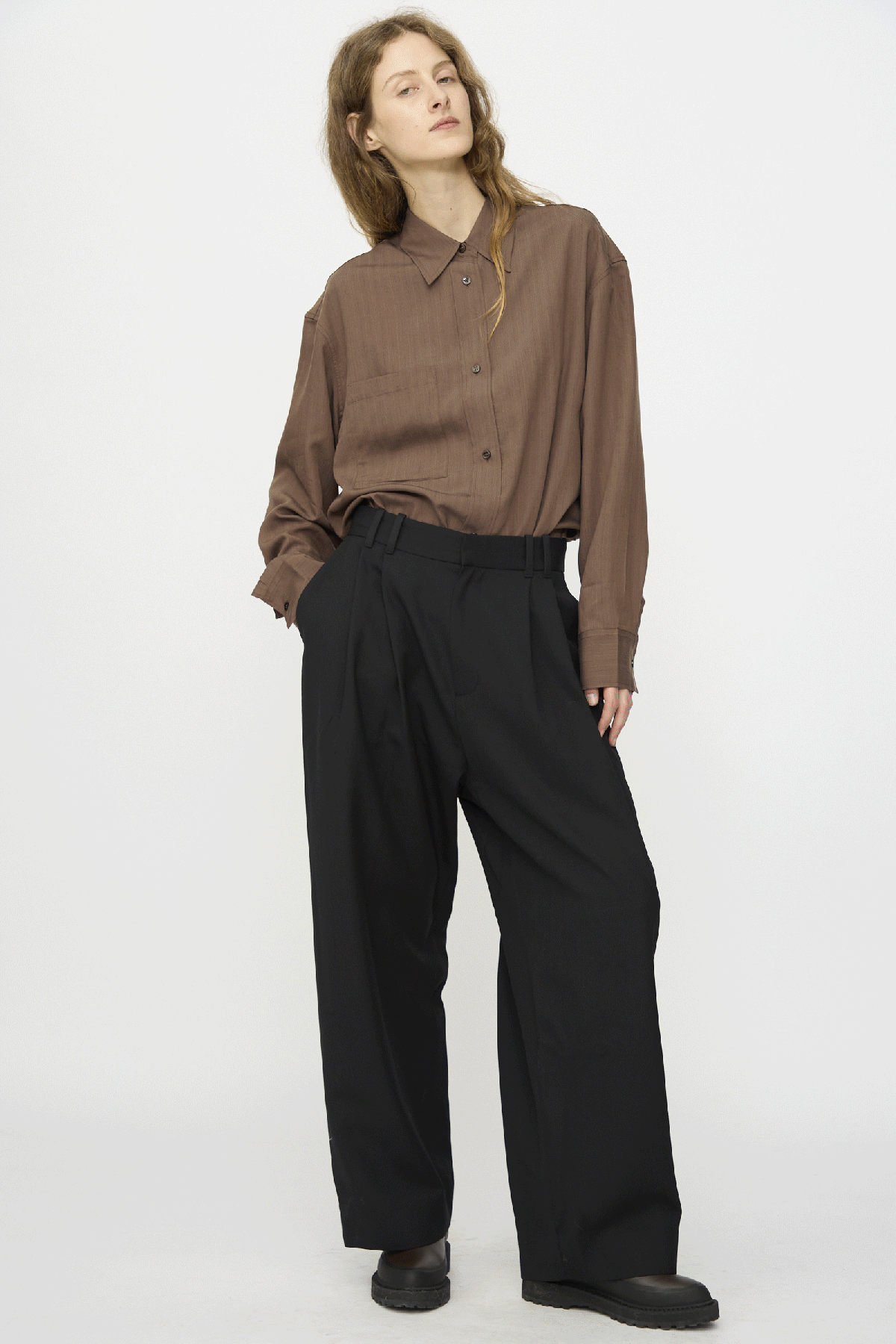 A gif of a woman wearing pieces from Studio Nicholsons FW25 collection against a white background.