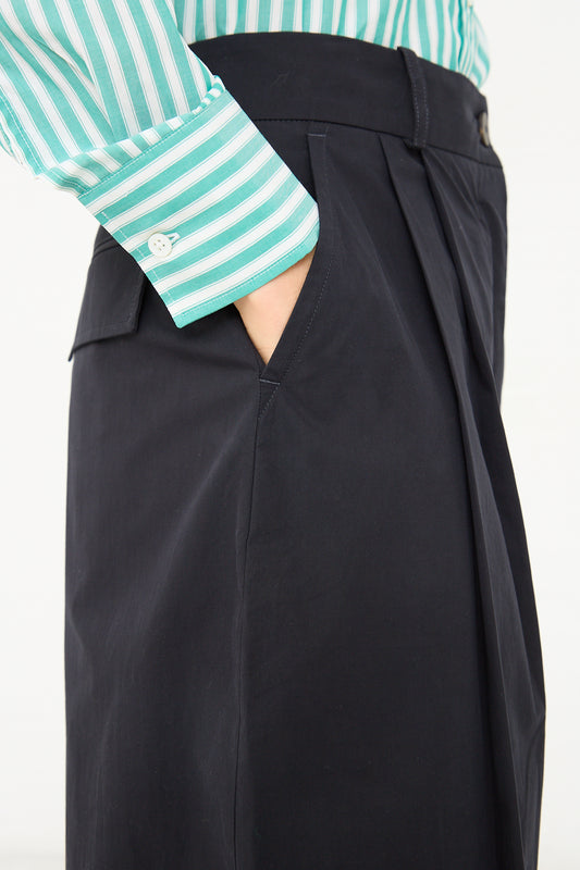 A woman wearing a striped shirt and Studio Nicholson Acuna Double Pleat Front Pant in Darkest Navy.