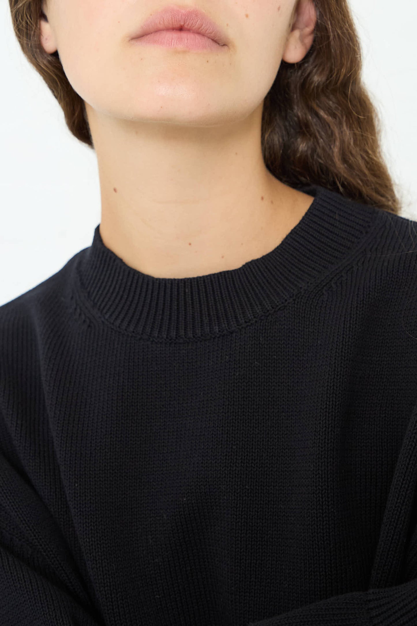 Close-up of a person wearing a Studio Nicholson Cotton Rib Paola Crewneck in Dark Navy, emphasizing the fabric texture and collar detail. Only the lower part of their face, neck, and shoulders are visible.