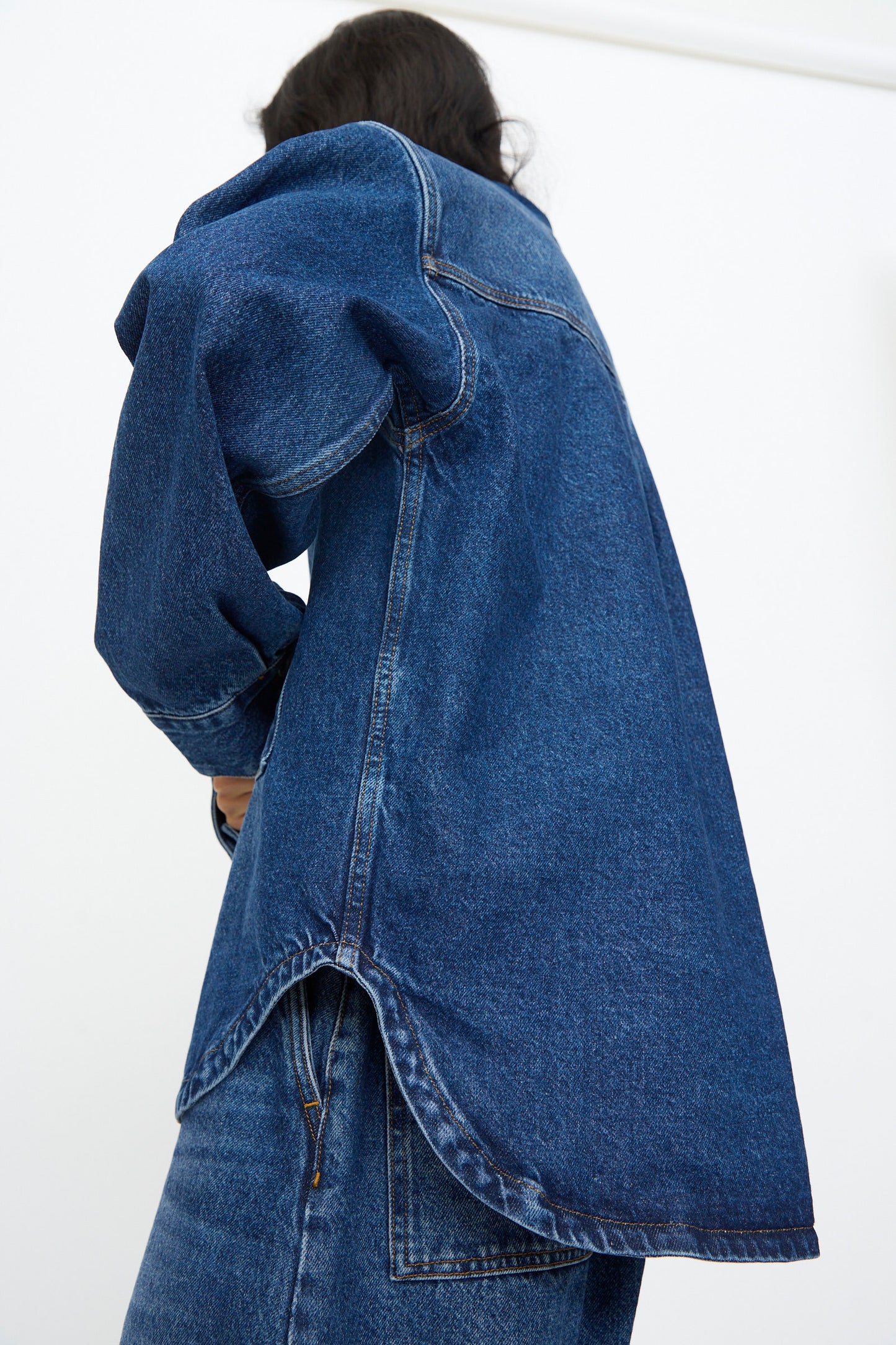 Person wearing the Studio Nicholson Denim Paso Shirt in Worn Wash Indigo, styled with matching blue jeans, photographed from behind against a plain white background.