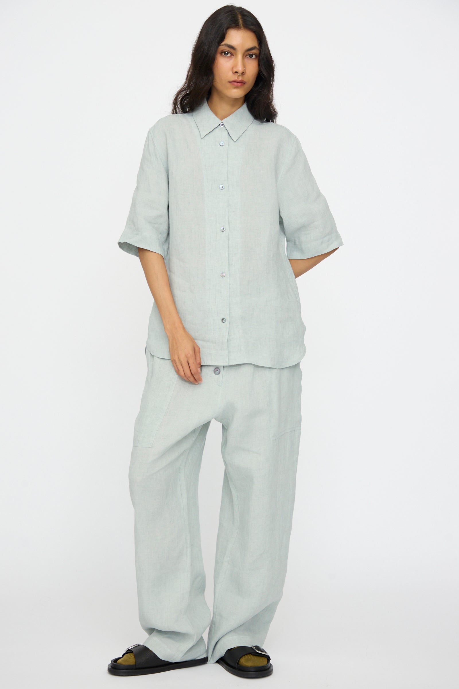 Model wearing the Studio Nicholson Estes Shirt in Spearmint, a relaxed fit linen shirt with short sleeves, paired with matching wide-leg pants against a plain white background.