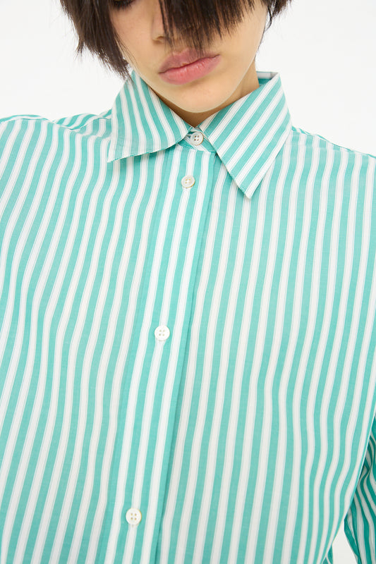 A person is wearing a Studio Nicholson Santos Overshirt in Green and Cream with buttons, and only the lower half of their face is visible.