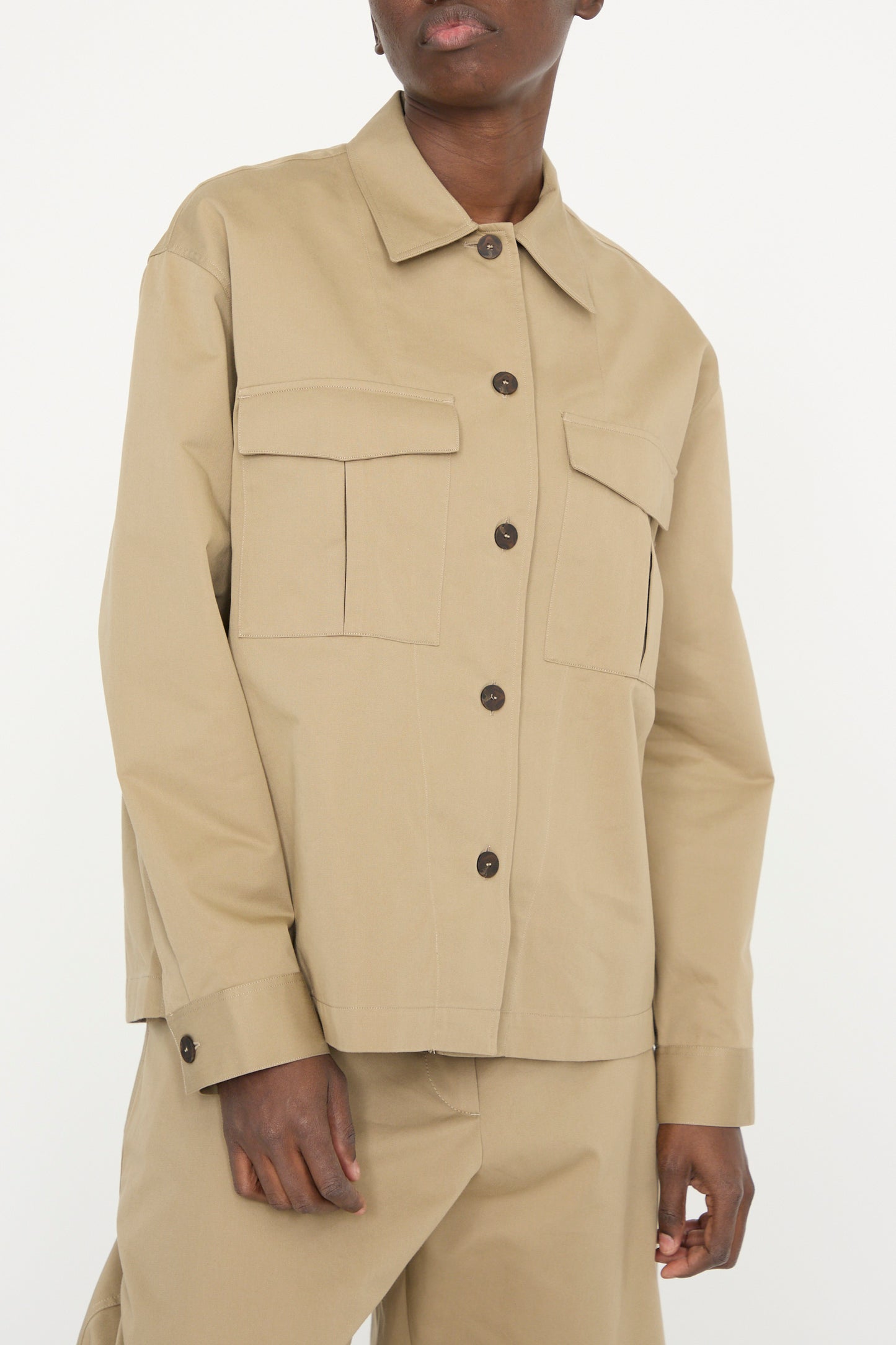 A person wearing Studio Nicholson's Soft Technical Twill Kukes Over Shirt in Parcel, featuring a boxy fit with large front pockets and matching pants, against a white backdrop. 