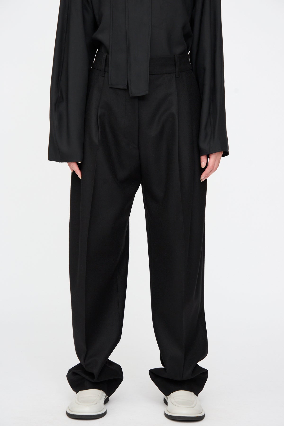 Black Sperro Double Pleat Pant in virgin wool with double front pleats and wide legs, worn with light-colored slip-on shoes.