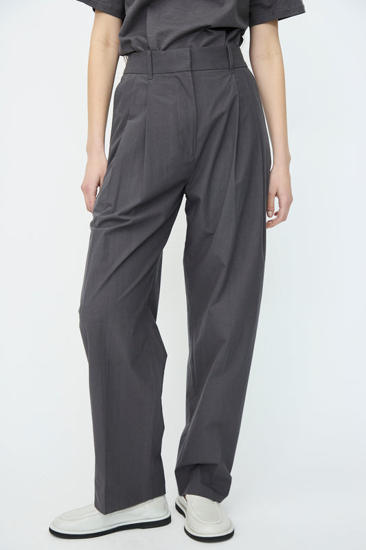 A person wearing Studio Nicholson's Typewriter Cotton Sperro Pant in Thunder and white shoes stands against a neutral background.