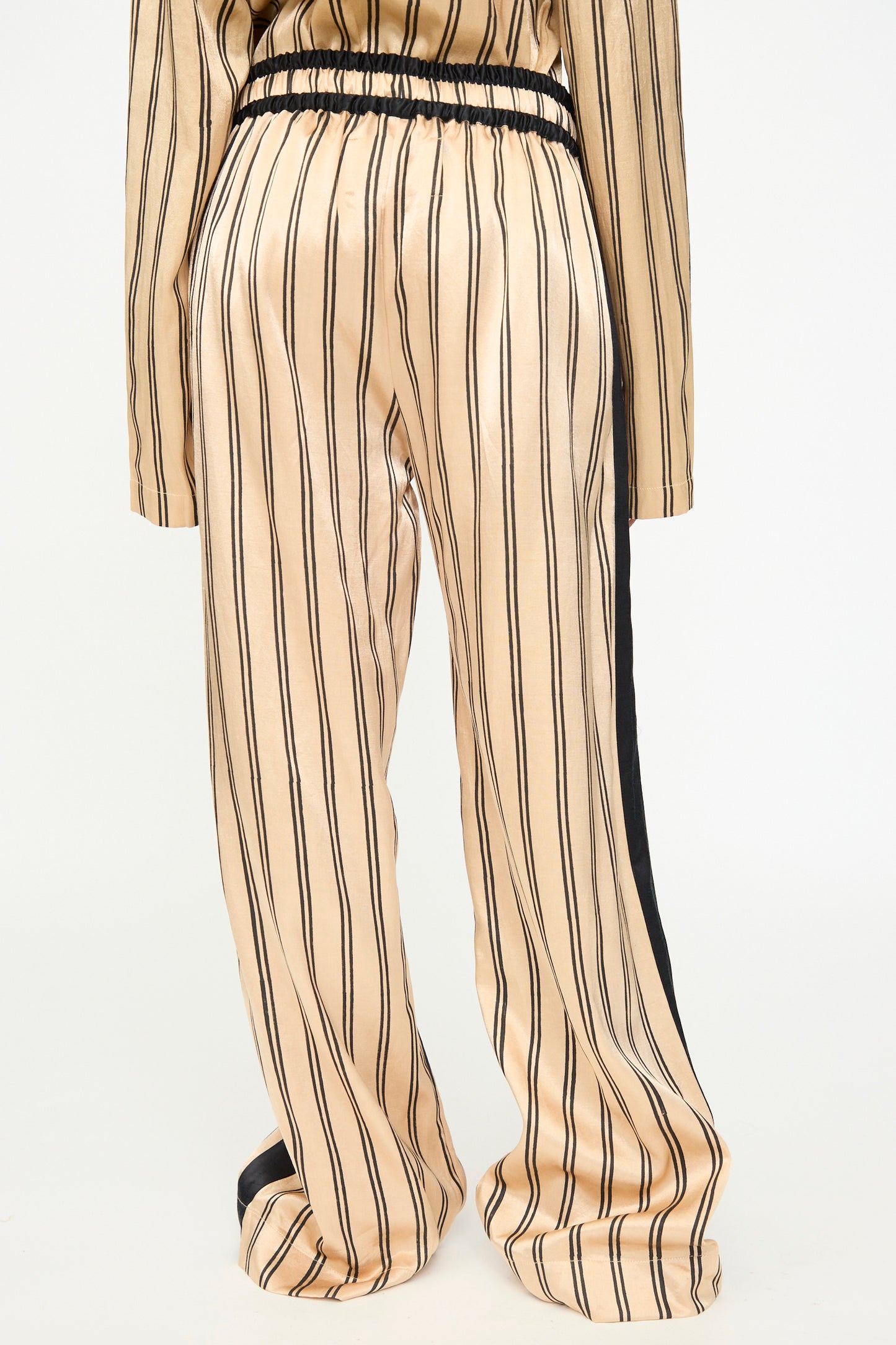 Model wearing the TIGRA TIGRA Block Printed Boxing Pant in Champagne and Black, featuring a relaxed boxing pant style with vertical black stripes on loose, beige silk mashroo. Styled with a matching top, each piece is handmade in India and shown here against a plain white background.