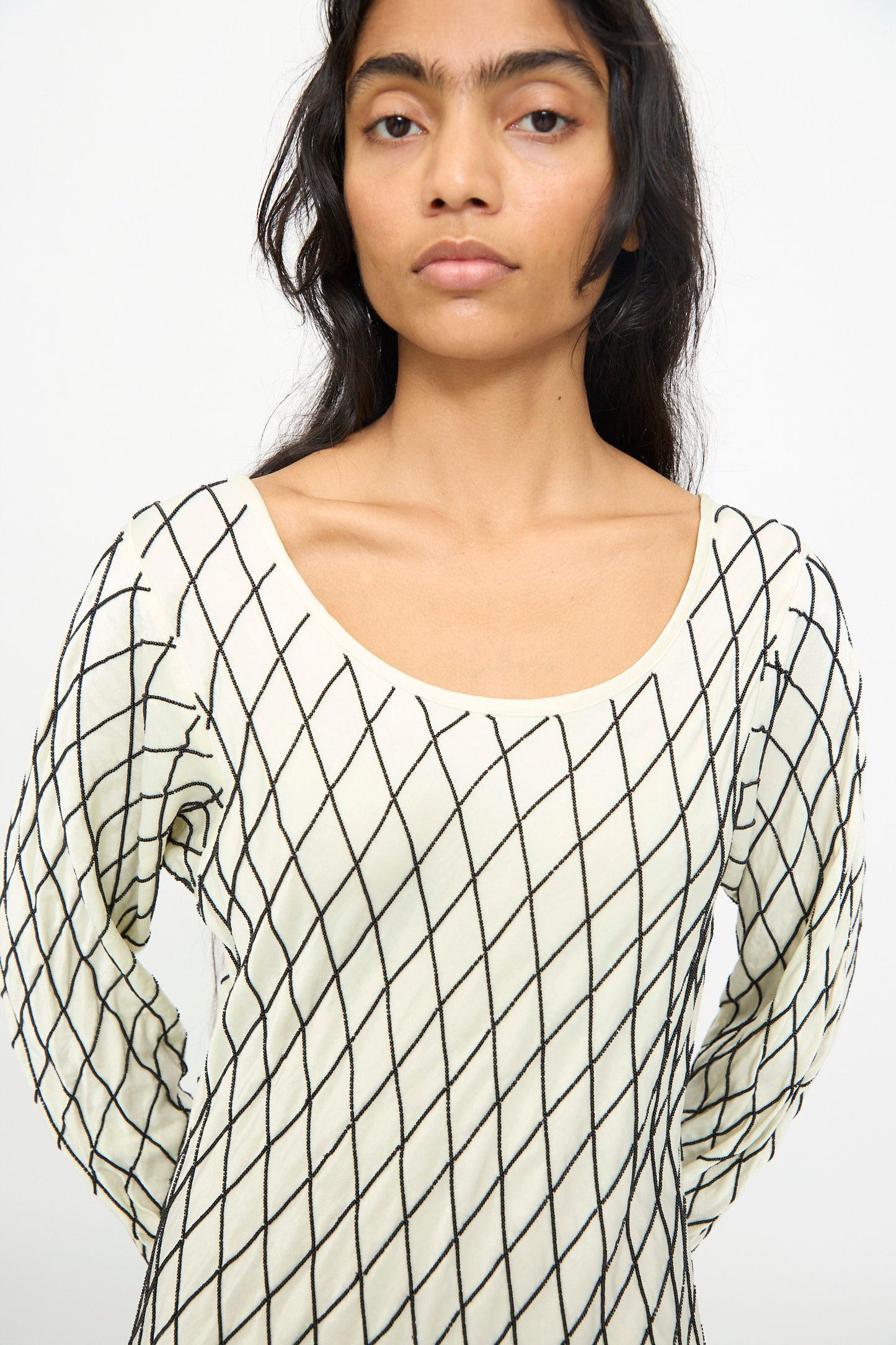 A person wearing the TIGRA TIGRA Off the Shoulder Dress in Pale Yellow with Black Glass Beads stands against a plain white background.