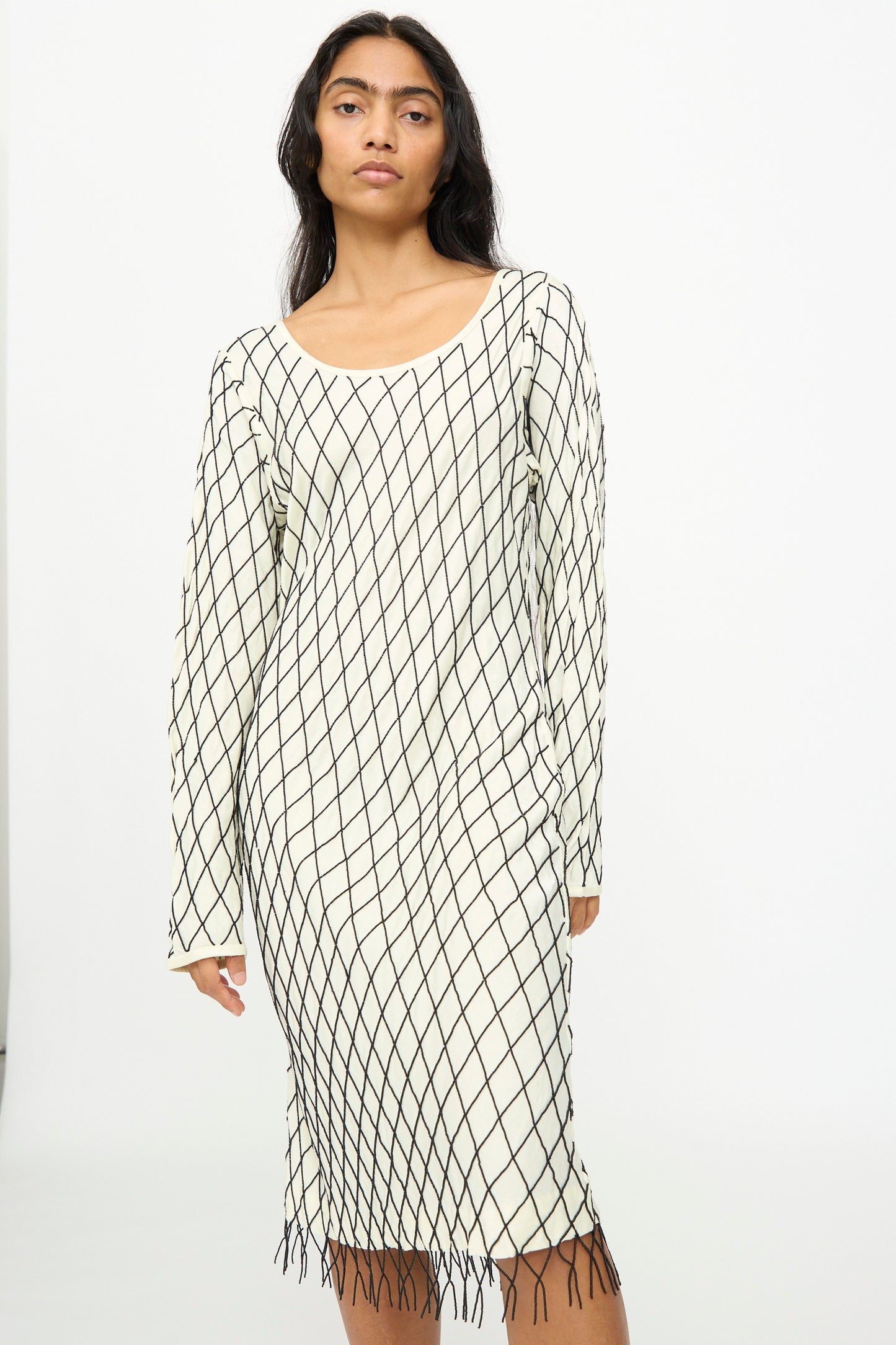 A woman wears the TIGRA TIGRA Off the Shoulder Dress in pale yellow adorned with black glass beads, standing against a plain white background.