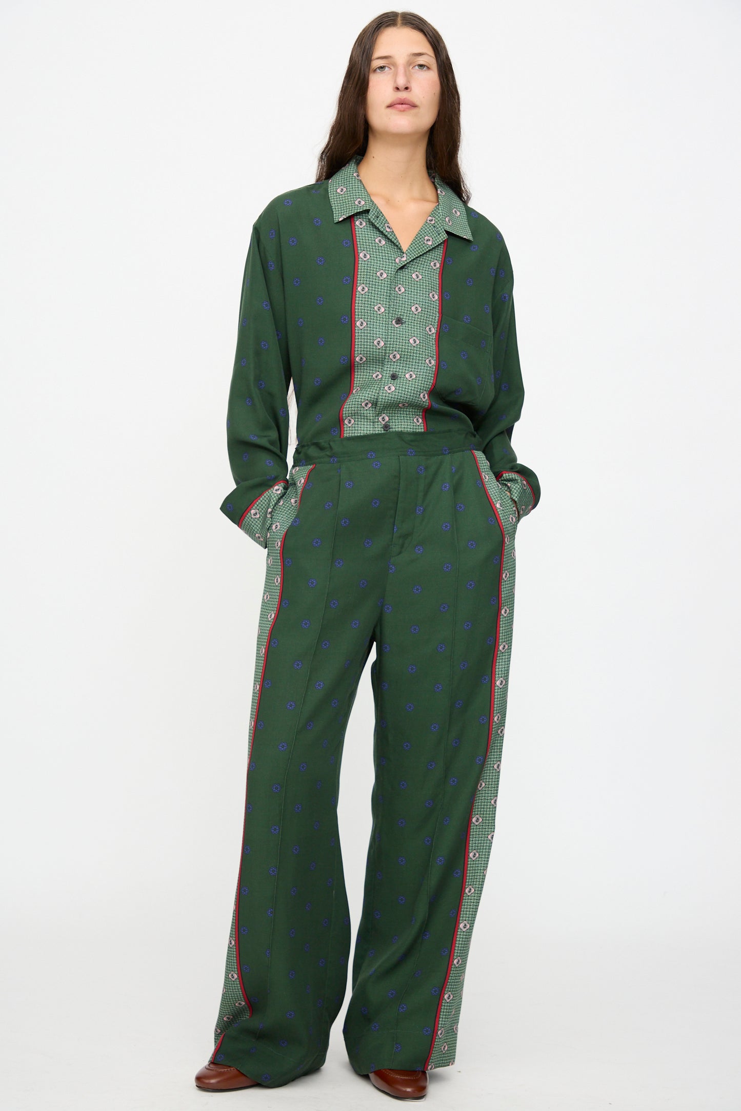 A person stands against a white background wearing TOGA ARCHIVES Inner Print Drawstring Pant in Green, styled with hands in the pockets.
