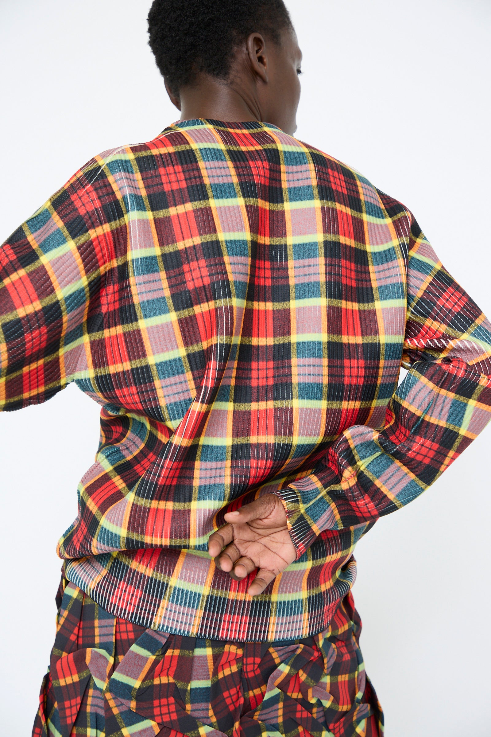 A person facing away, with one hand tucked behind their back, wearing the TOGA ARCHIVES Print Knit Pullover in Red.