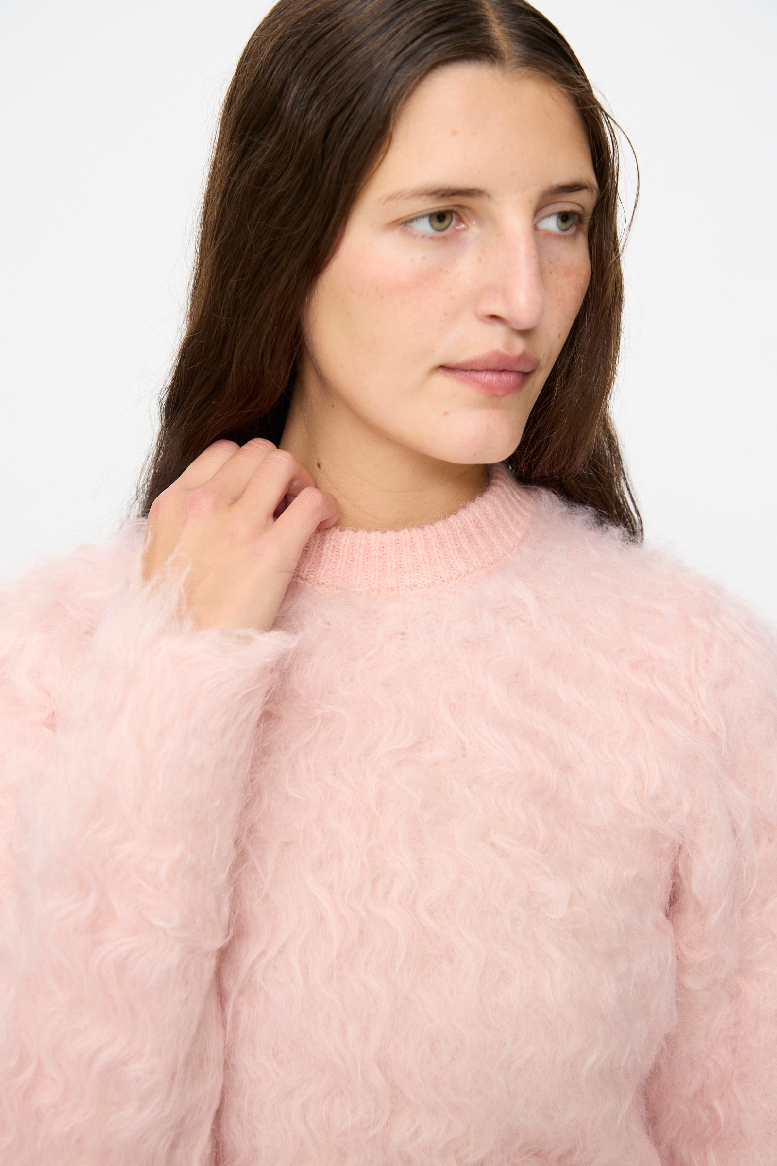 A person with long brown hair wearing the TOGA ARCHIVES Shaggy Knit Pullover in Pink looks to the side against a plain background.