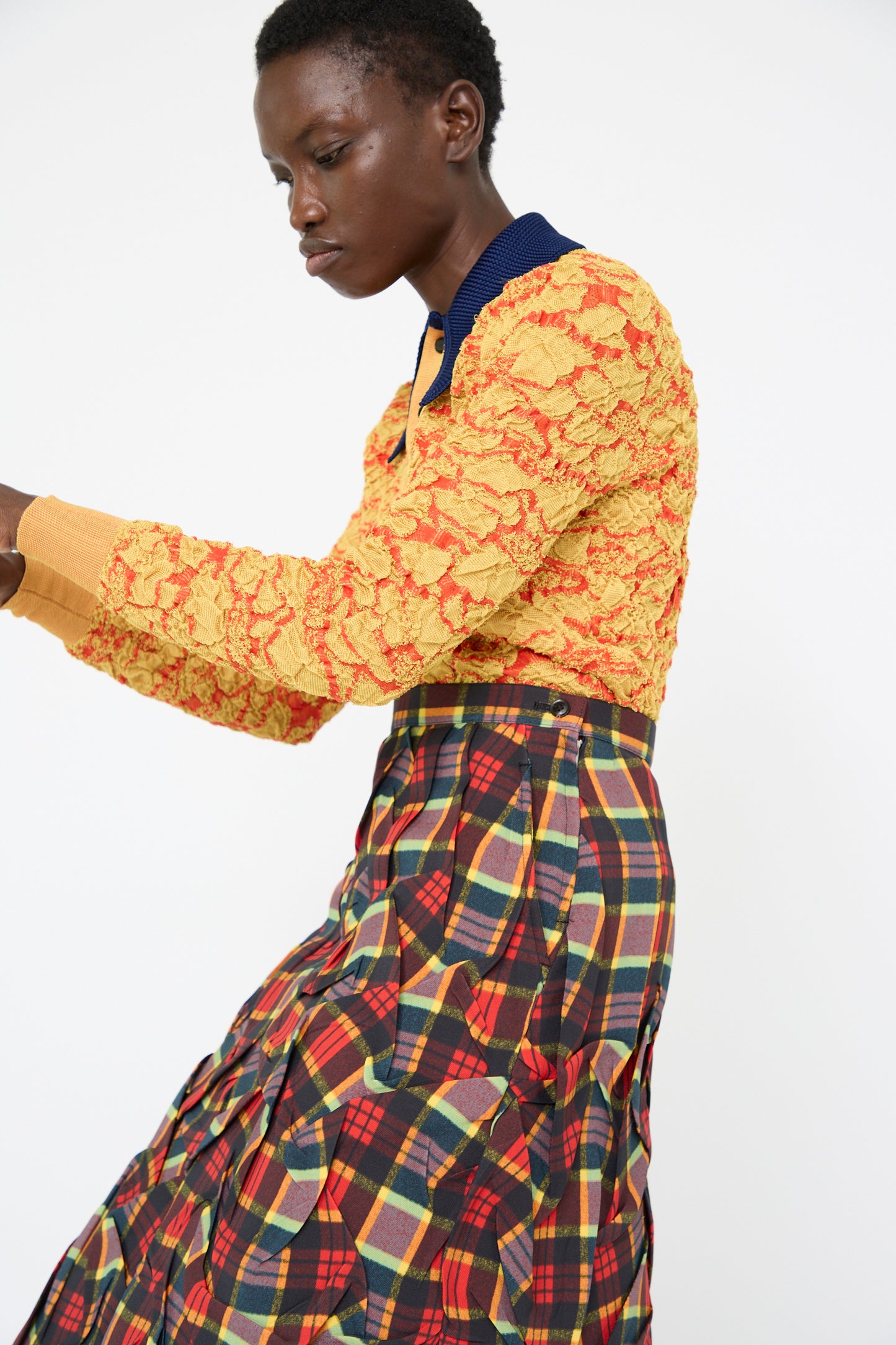 A person wearing a textured yellow top and the Twill Plaid Skirt in Red by TOGA ARCHIVES, set against a white background.