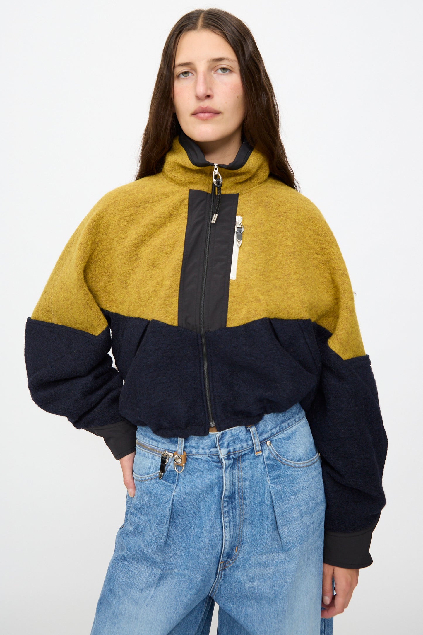 A woman wearing the Wool Jersey Blouson in Navy by TOGA ARCHIVES with light blue high-waisted jeans, standing against a plain white background.
