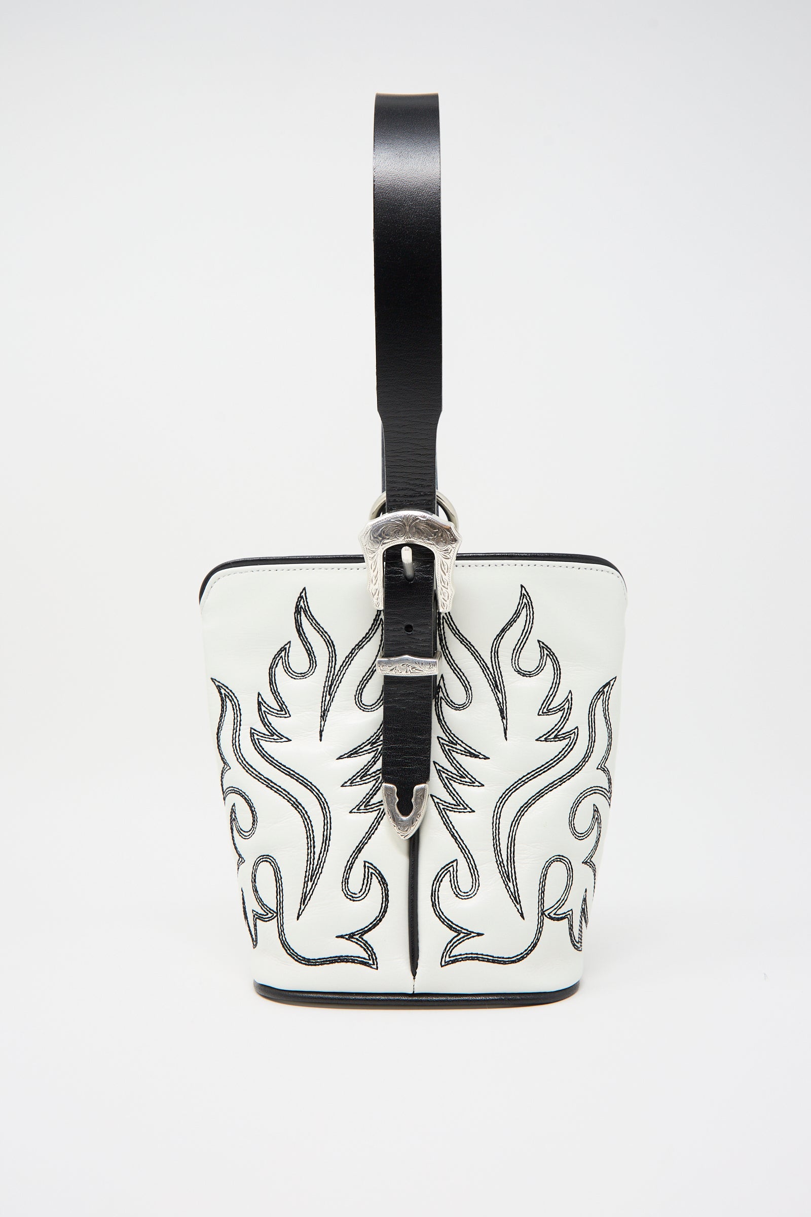 The Western Leather Handbag in White by TOGA ARCHIVES is a small, structured leather bag featuring black stitched flame designs and a sleek black leather strap with a silver buckle, perfect for those who appreciate western motif embroidery.