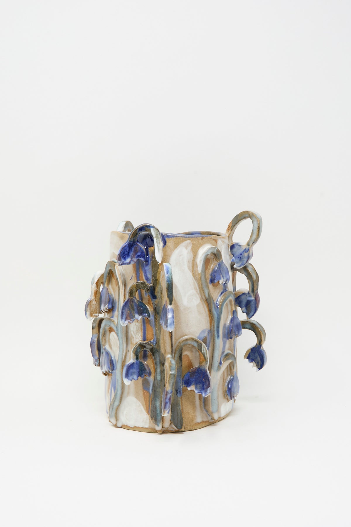 Tamar Mogendorff Bluebell Field Vase, a cylindrical handmade ceramic vase decorated with raised, sculptural blue and white bell-shaped flowers.