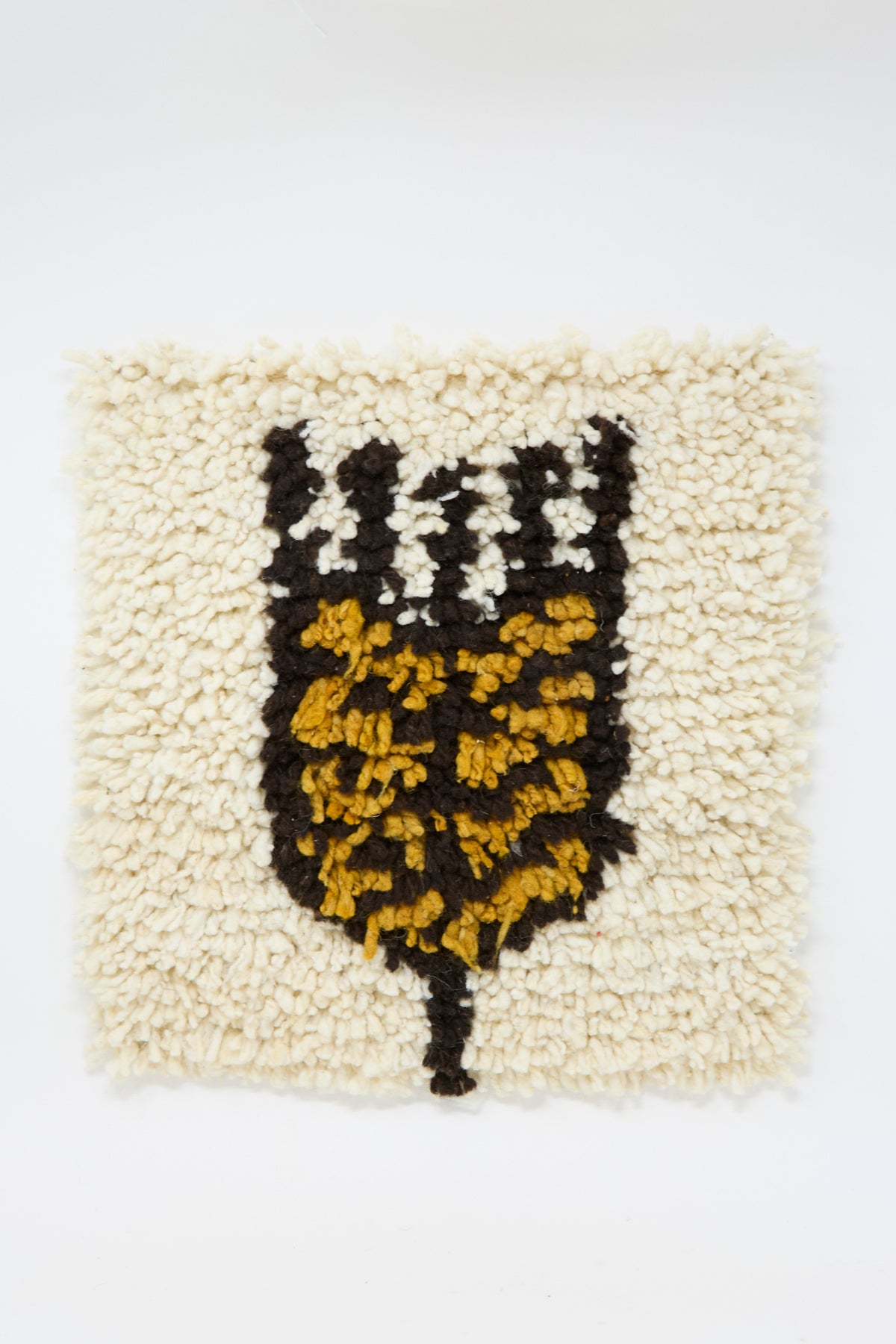 Tamar Mogendorff Chair Rug in Natural: a square tufted artisan rug with an off-white background and a black and yellow wheat design. 