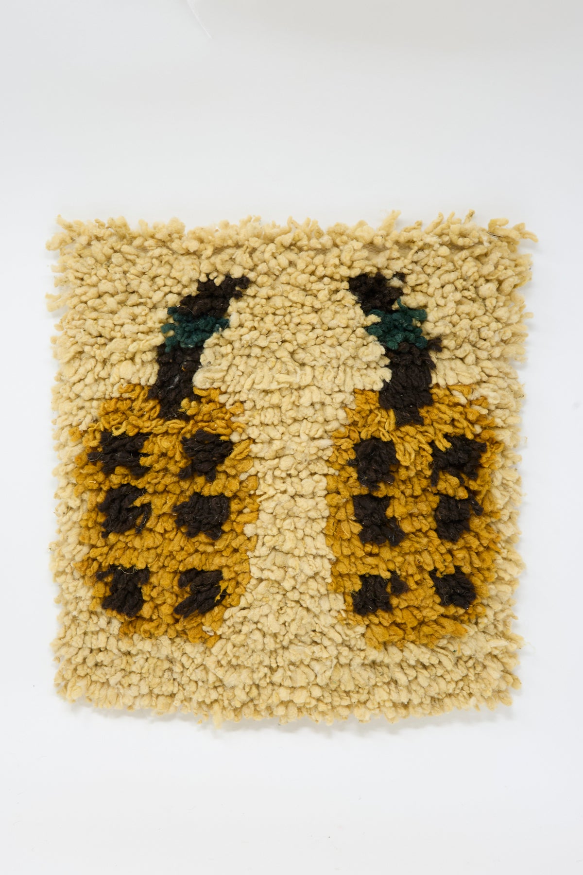 Tamar Mogendorff Chair Rug in Oat: a square rug with a beige tufted background featuring two yellow and brown spotted date motifs with dark stems.