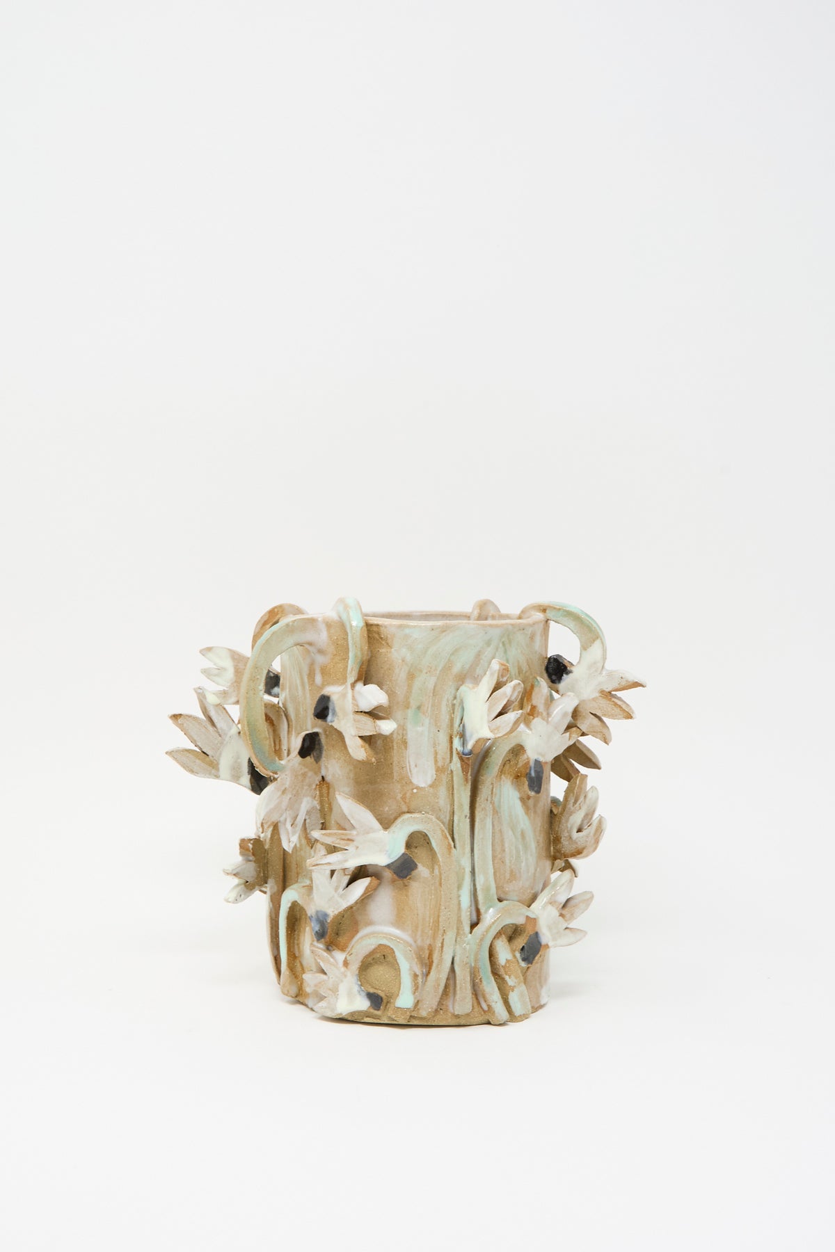 Tamar Mogendorff Cyclamens Field Vase, a handmade cylindrical ceramic piece from Brooklyn featuring raised, sculpted flowers in muted green, white, and dark blue.