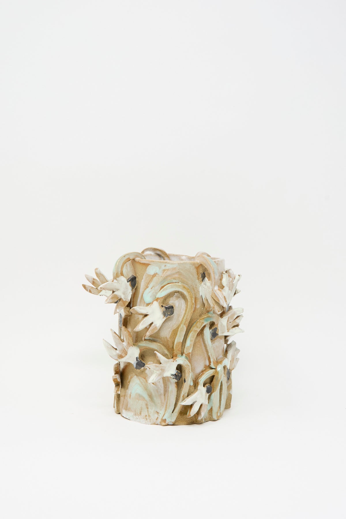 Tamar Mogendorff Cyclamens Field Vase, a handmade cylindrical ceramic piece from Brooklyn featuring raised, sculptural cyclamen flowers and swirling stems in tan, green, and white.