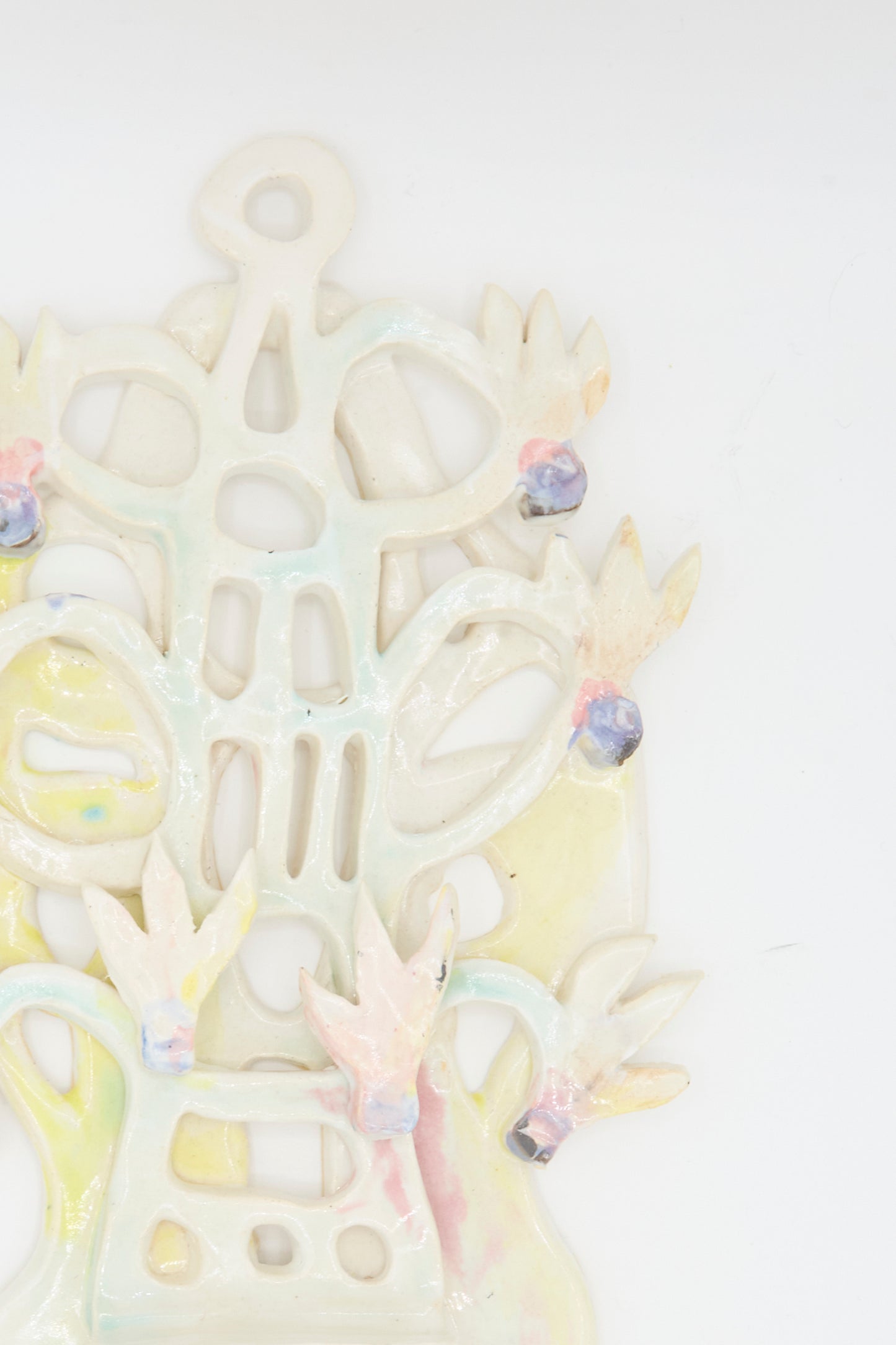 The Cyclamens Wall Piece by Tamar Mogendorff is a pastel-colored handmade ceramic art sculpture featuring abstract shapes and bird-like figures, standing out beautifully against a white background.