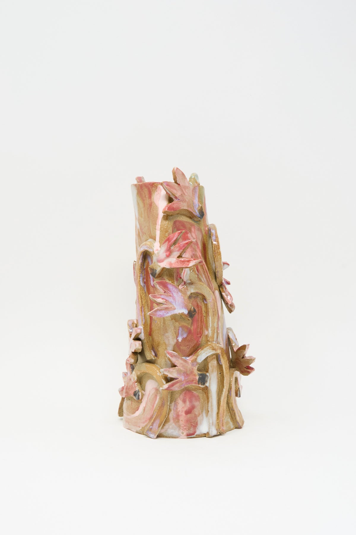 Cyclamens in the Wild Vase I, a handmade ceramic vase decorated with three-dimensional sculpted flowers and leaves in a multicolored glaze of pink, tan, and cream.