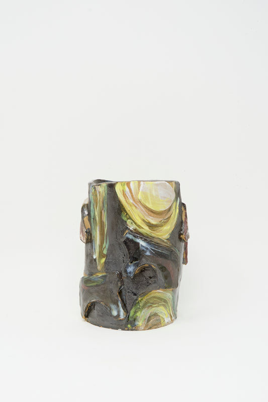 The Donkeys in the Moonshine vase by Tamar Mogendorff is a dark, cylindrical handmade Brooklyn ceramic with abstract yellow and green swirled patterns on its textured surface, shown against a plain white background.