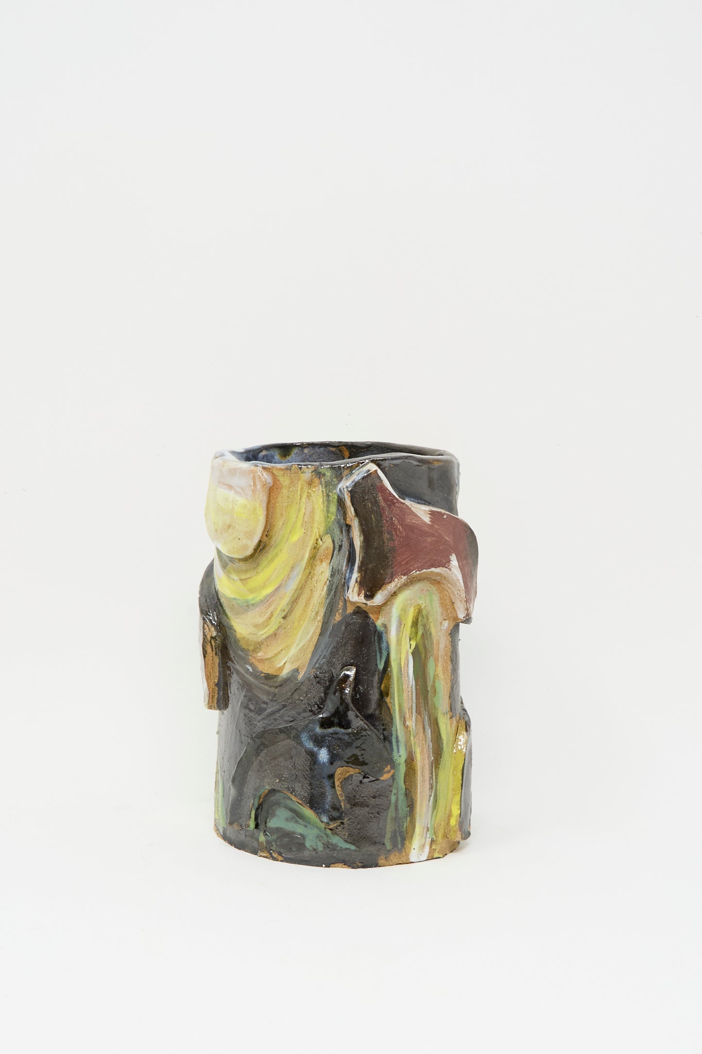 The “Donkeys in the Moonshine” vase by Tamar Mogendorff is a handmade cylindrical ceramic with an uneven surface and abstract multicolored glazes—yellow, brown, green, black—shown on a plain white background.
