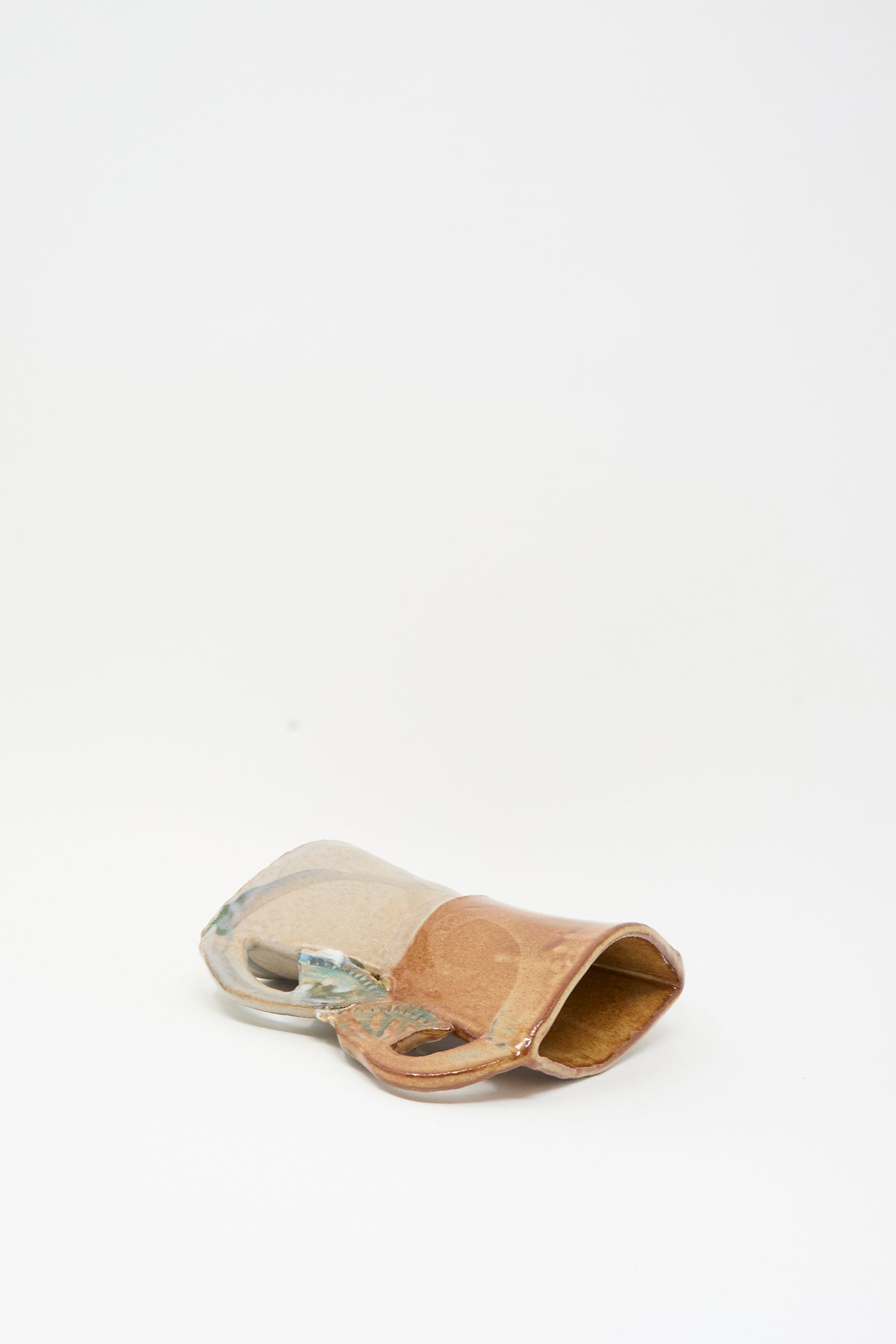 Tamar Mogendorff’s Four Papyrus Vase, a two-toned ceramic vase with four small handles, lying on its side.