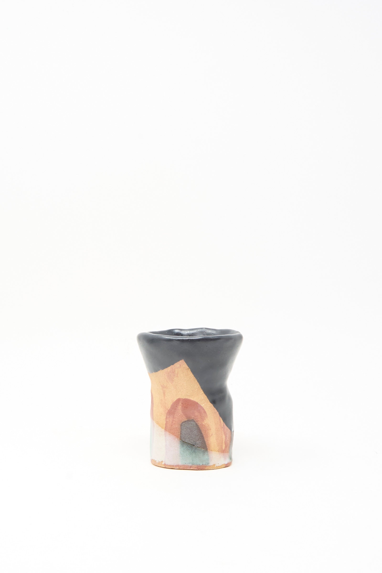 The I wish I knew them Candleholder II by Tamar Mogendorff is a small handmade ceramic piece with a glossy black and orange top and abstract multicolored design on the lower half, shown against a plain white background.