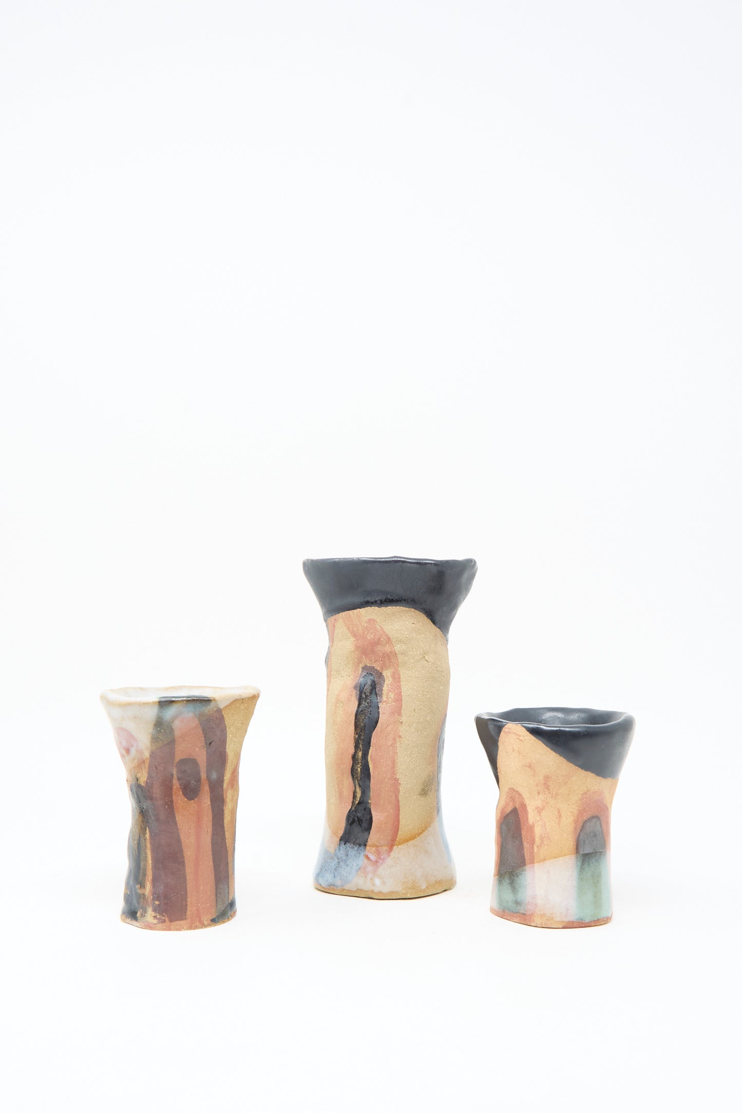 Three "I wish I knew them Candleholder III" ceramic candleholders by Tamar Mogendorff, featuring flared rims and abstract black and orange glaze patterns, are arranged side by side on a white background.