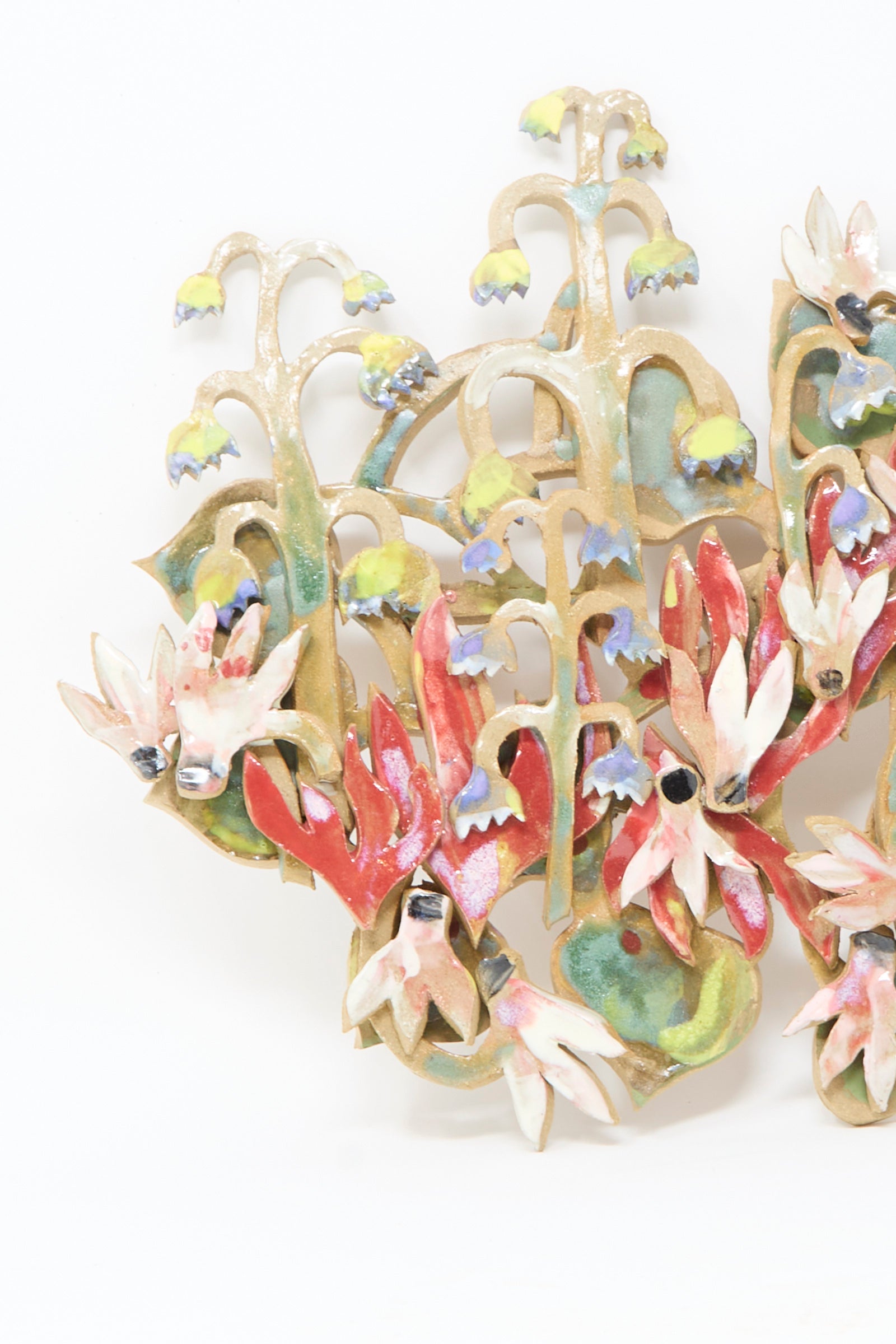 The "My Garden is on Fire Wall Relief" by Tamar Mogendorff is a handmade Brooklyn ceramic wall art featuring stylized flowers in red, white, and purple with green stems—a unique floral piece for any space.