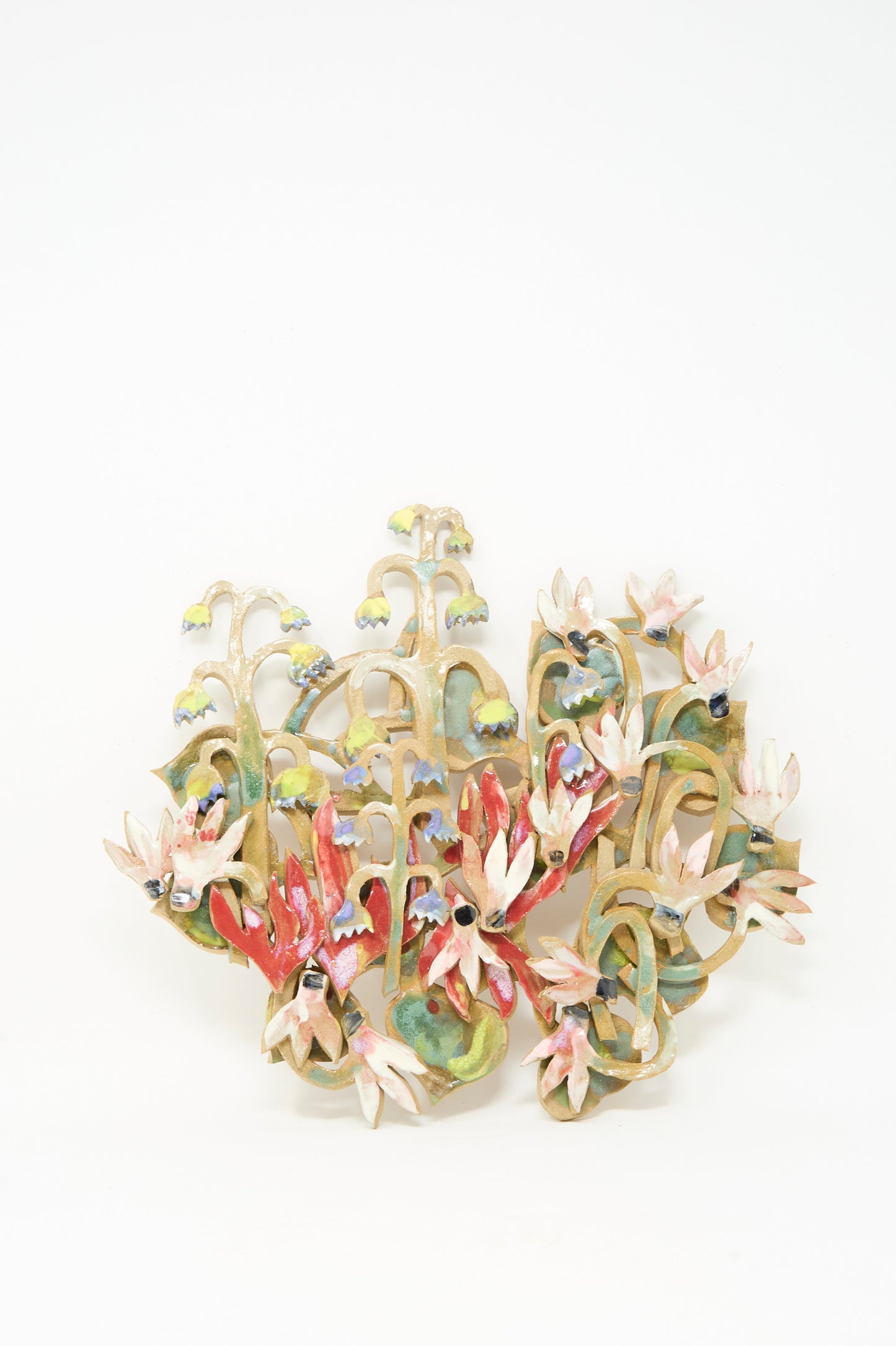The "My Garden is on Fire Wall Relief" by Tamar Mogendorff features handmade, abstract ceramic flowers and leaves in vibrant layers, artfully clustered against a white backdrop for striking wall decor.