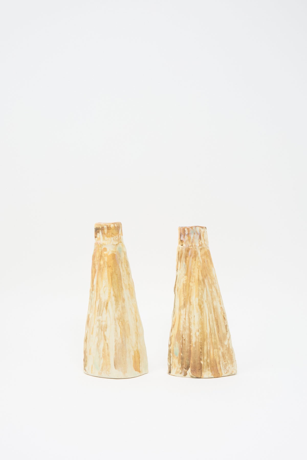 Two On Top of the Mountain Candle Holders, cone-shaped ceramic candle holders with a textured finish and a streaked tan and cream glaze.