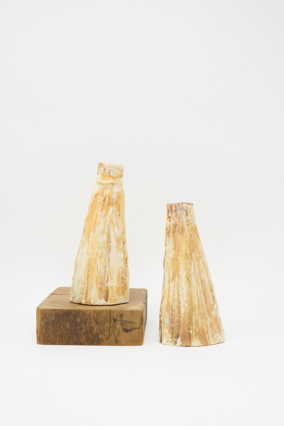Two On Top of the Mountain Candle Holders with a textured, light brown glazed finish, one resting on a square wooden block.