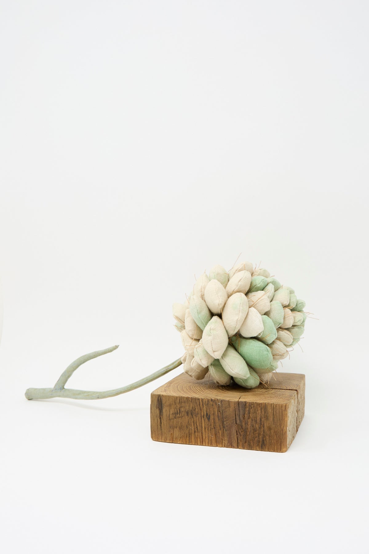 Tamar Mogendorff Pine Cone No. 2, a handmade fabric pinecone ornament in shades of cream and sage, resting on a small wooden block.