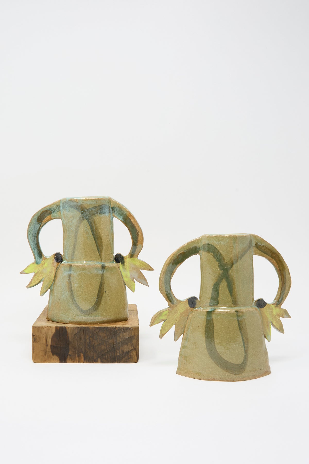 Two Cyclamens Vase in Celadon Green I: two handmade celadon green ceramic vases with decorative petal-like handles, one set on a wooden block.